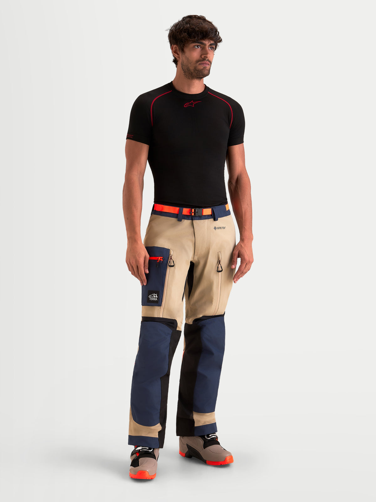 Alpinestars Arenis Gore-Tex Hose, Herren-Abenteuer-Motorradhose in Marineblau, Beige und Schwarz, Vorderansicht an einem Model mit schwarzem T-Shirt, mit wasserdichter GORE-TEX-Konstruktion und Cargotasche