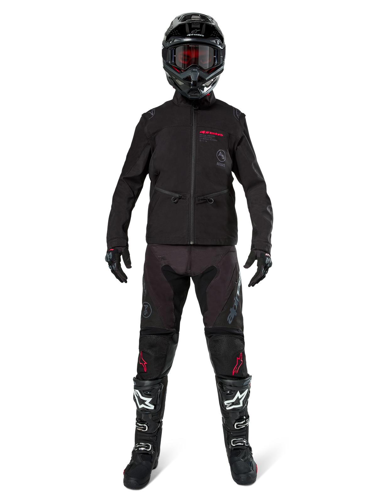 Motocross-Fahrer in der Alpinestars Lite-Dura Softshell-Jacke in Schwarz mit roten Logo-Details, kombiniert mit passender schwarzer Offroad-Hose, schwarzem Helm und weiß-schwarzen Stiefeln, komplette professionelle Enduro-Rennausrüstung