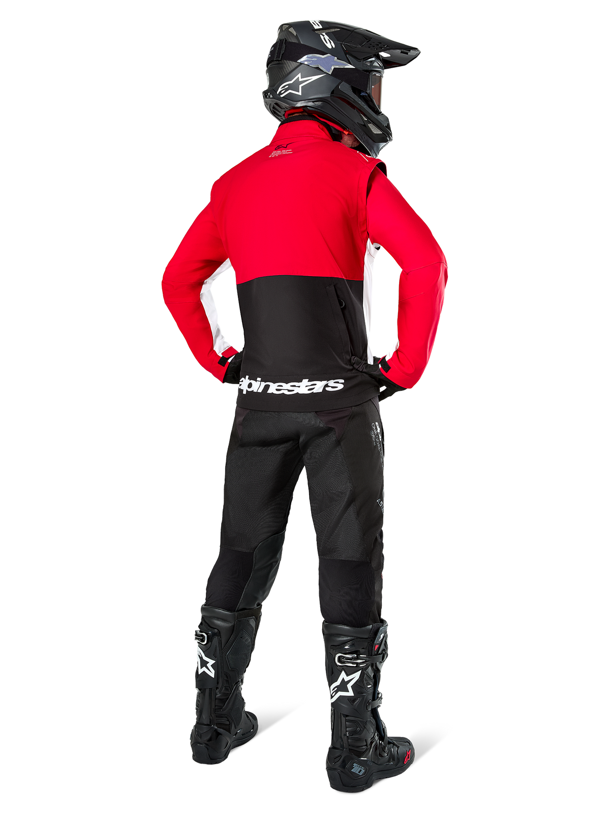 Motocross-Fahrer von hinten in der Alpinestars Lite-Dura Softshell-Jacke, Schwarz, Bright Red und Weiß, mit rotem oberen Panel und schwarzem unteren Bereich mit weißem Branding, kombiniert mit schwarzer Hose, schwarzem Helm und schwarzen Stiefeln, abgestimmtes Enduro-Outfit für Geländefahrten