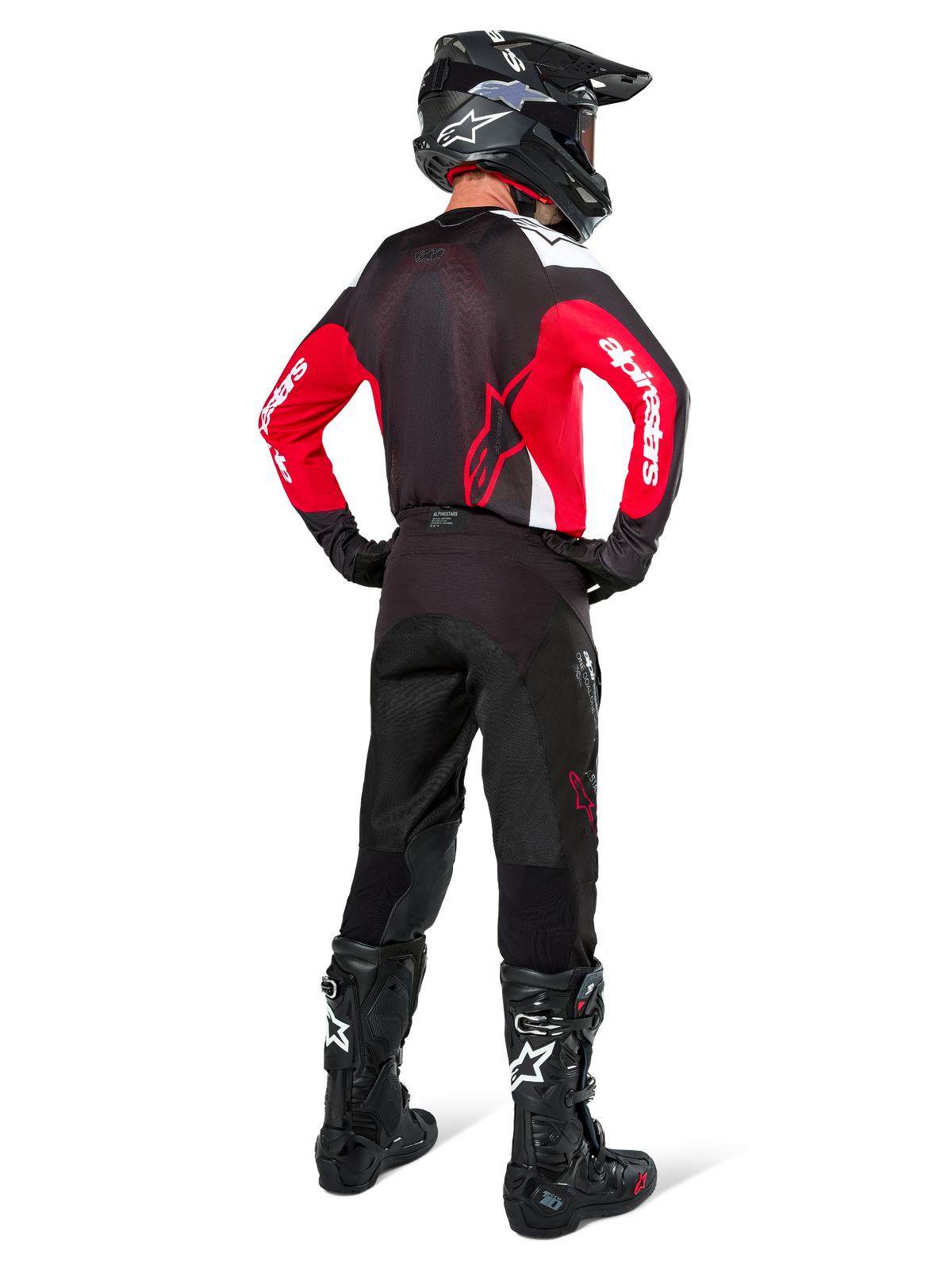 Motocross-Fahrer von hinten in Alpinestars Pro-Dura Hose in Black Magnet White, kombiniert mit einem rot-schwarzen Trikot und schwarzen Stiefeln, abgestimmtes Offroad-Ausrüstungsset für Enduro-Fahrten