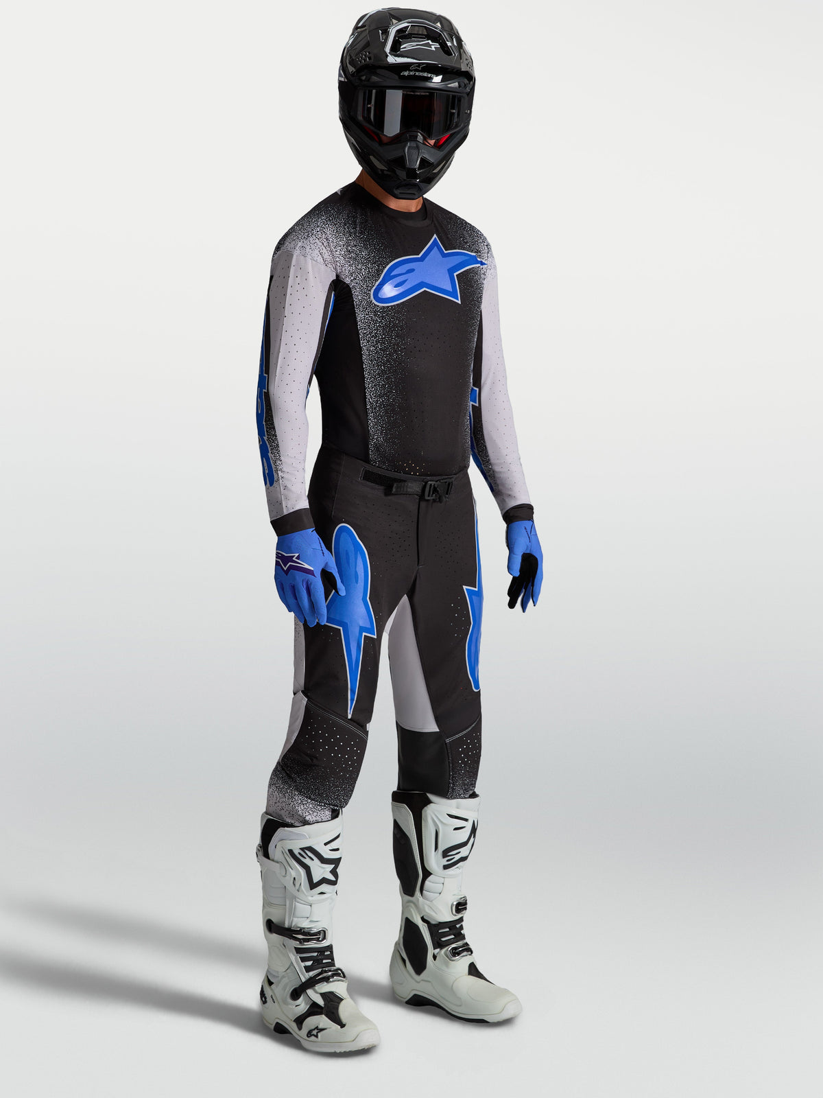 Alpinestars Supertech Hiten AFD Hose, Motocross-Set für Herren in Schwarz und Blau am Model mit Trikot und weißen Stiefeln.