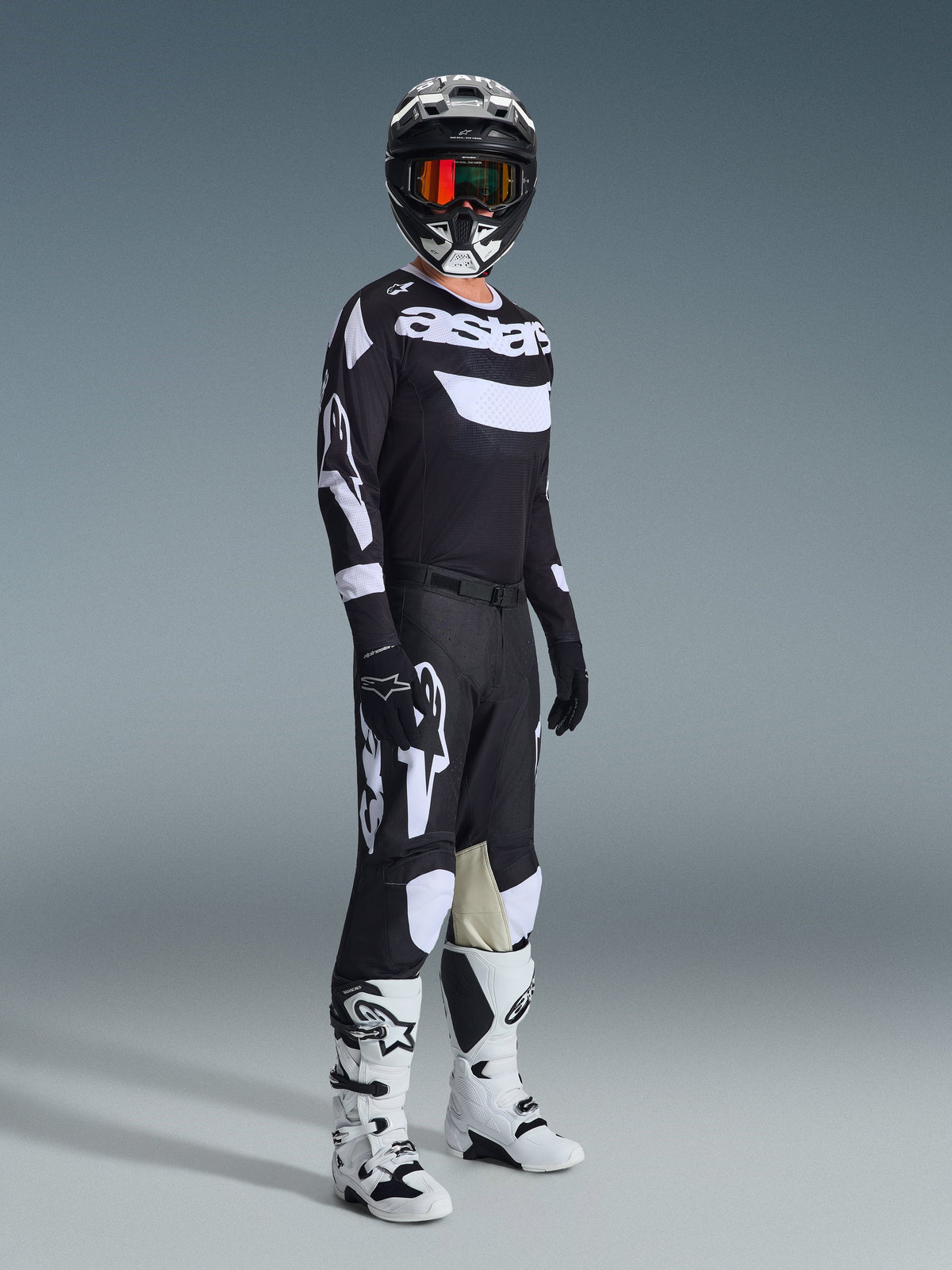 Motocross-Fahrer in der 2026 Racer Air Riway Hose, Schwarz und Weiß, passendes Trikot mit Alpinestars-Logo, schwarzer Helm mit Goggles, weiß-schwarze Stiefel, komplettes Ausrüstungs-Set für Offroad-Motocross-Performance