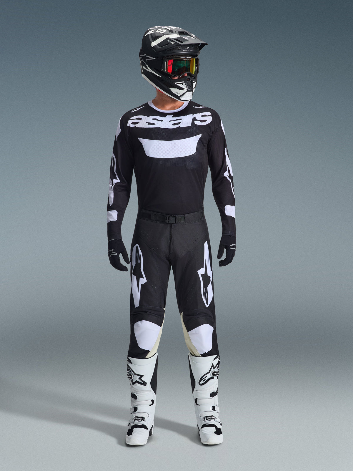 Motocross-Fahrer in Alpinestars 2026 Racer Air Riway Hose in Schwarz und Weiß, passendes schwarz-weißes Trikot mit „astars“-Logo, schwarzer Helm, Brille mit irisierenden Gläsern und weiße Rennstiefel, komplette professionelle Offroad-Ausrüstung