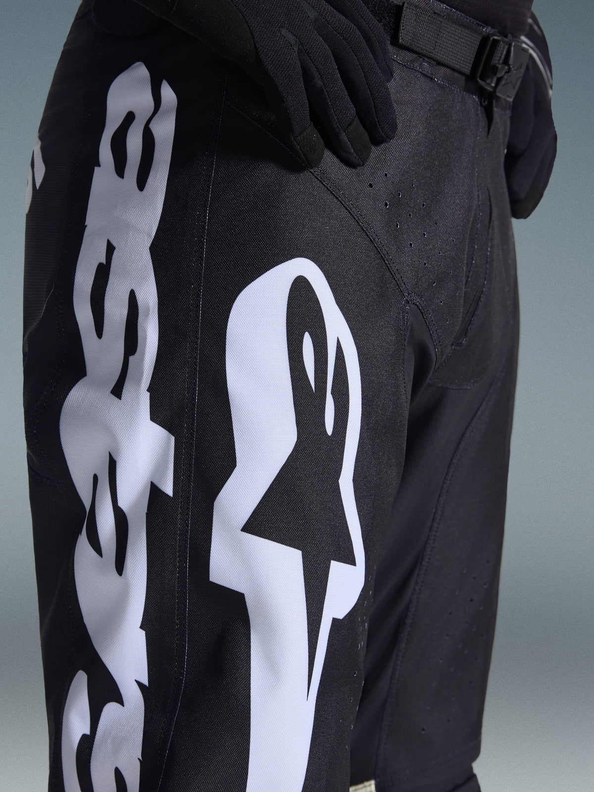 Alpinestars 2026 Racer Air Riway Hose, Motocross-Hose, Schwarz und Weiß, Detailansicht mit großem weißem Alpinestars-Branding, lasergeschnittenen Perforationen für Luftzirkulation und verstellbarer Taillenschnalle, strapazierfähiges Material für Offroad-Einsätze.