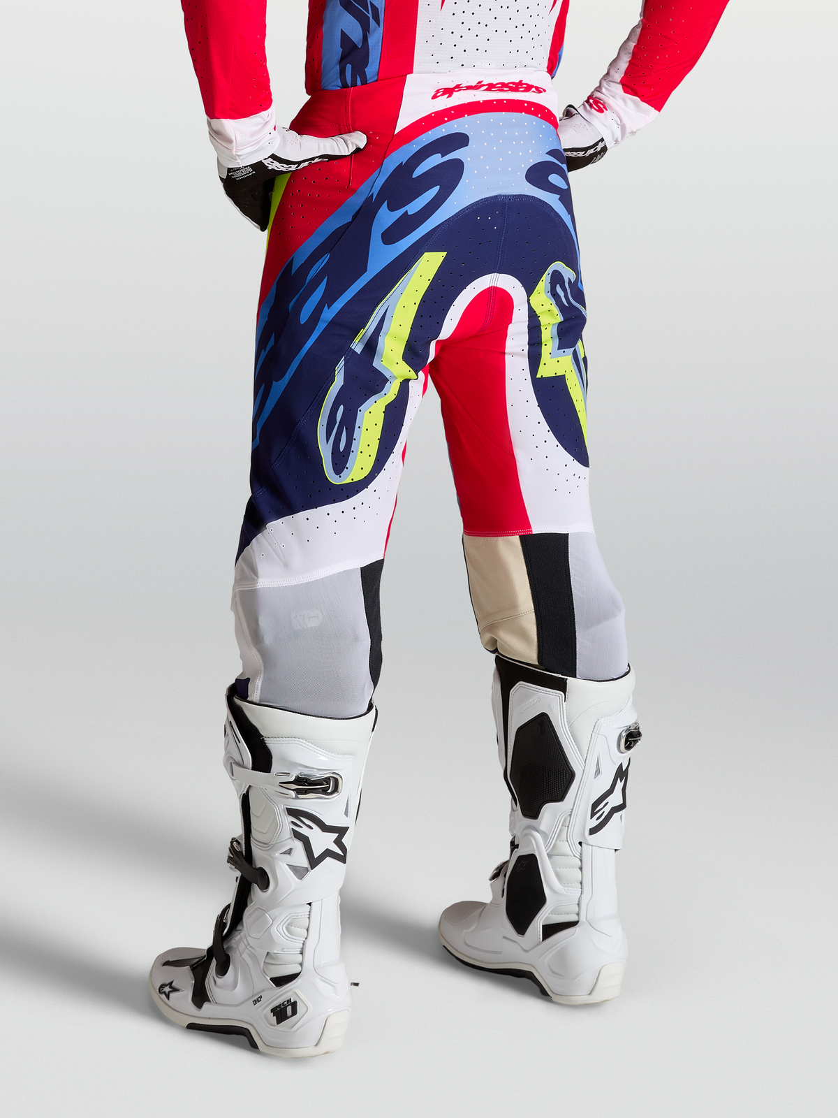 Alpinestars Supertech Dyna Hose, Motocross-Hose in Rot, Weiß und Navy-Blau, athletische Passform am Model, getragen mit weißen Tech 10 Stiefeln, rennerprobte Offroad-Performance-Ausrüstung für MX und SX.