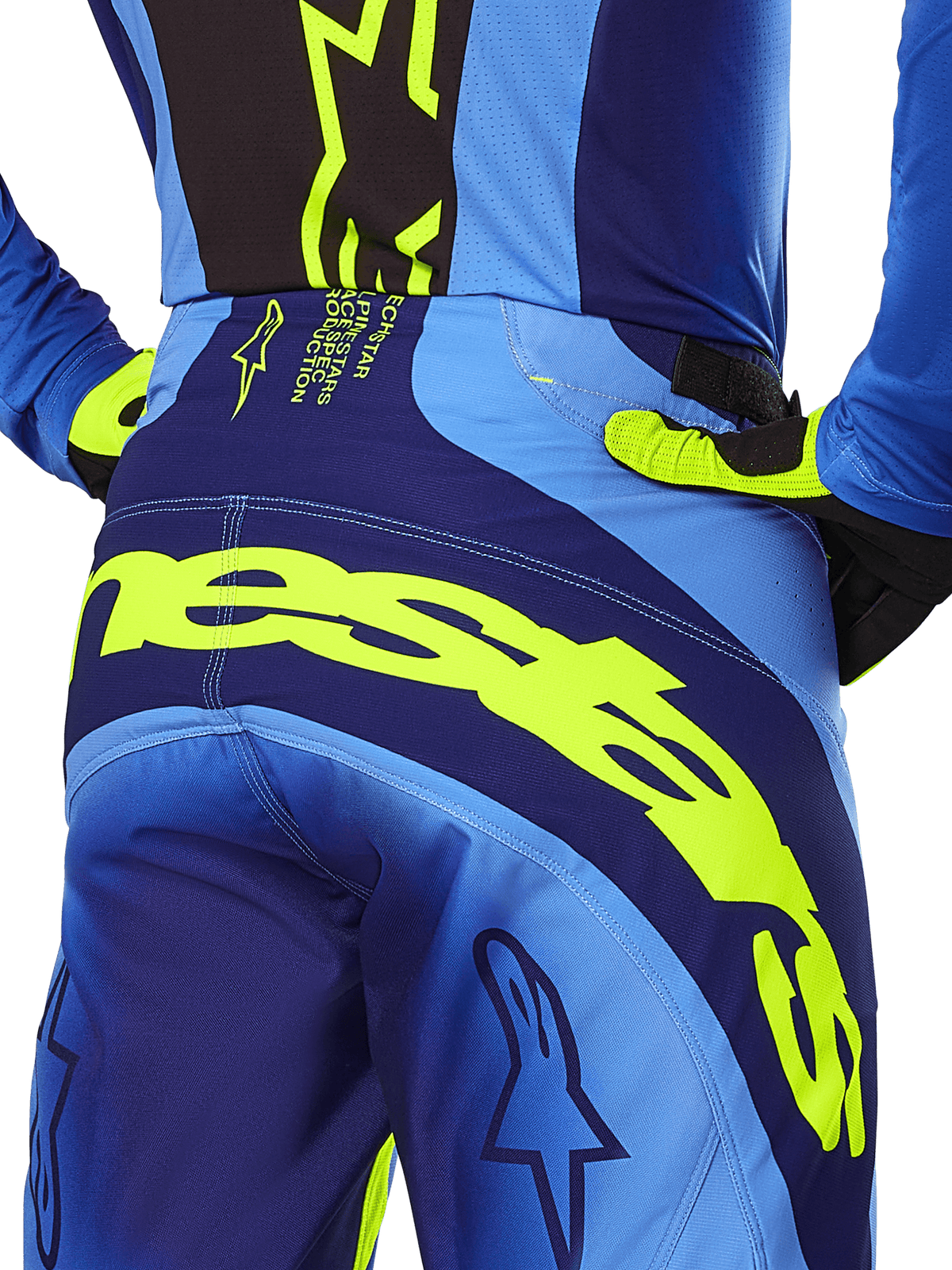 Alpinestars 2025 Techstar Melt Hose, Motocross-Hose, Gelb Fluo und Blau, Nahaufnahme der Rückansicht mit markantem gelbem Alpinestars-Branding am Gesäß, getragen mit passendem blauem Trikot und gelben Fluo-Handschuhen, konzipiert für Performance-Offroad-Rennsport.