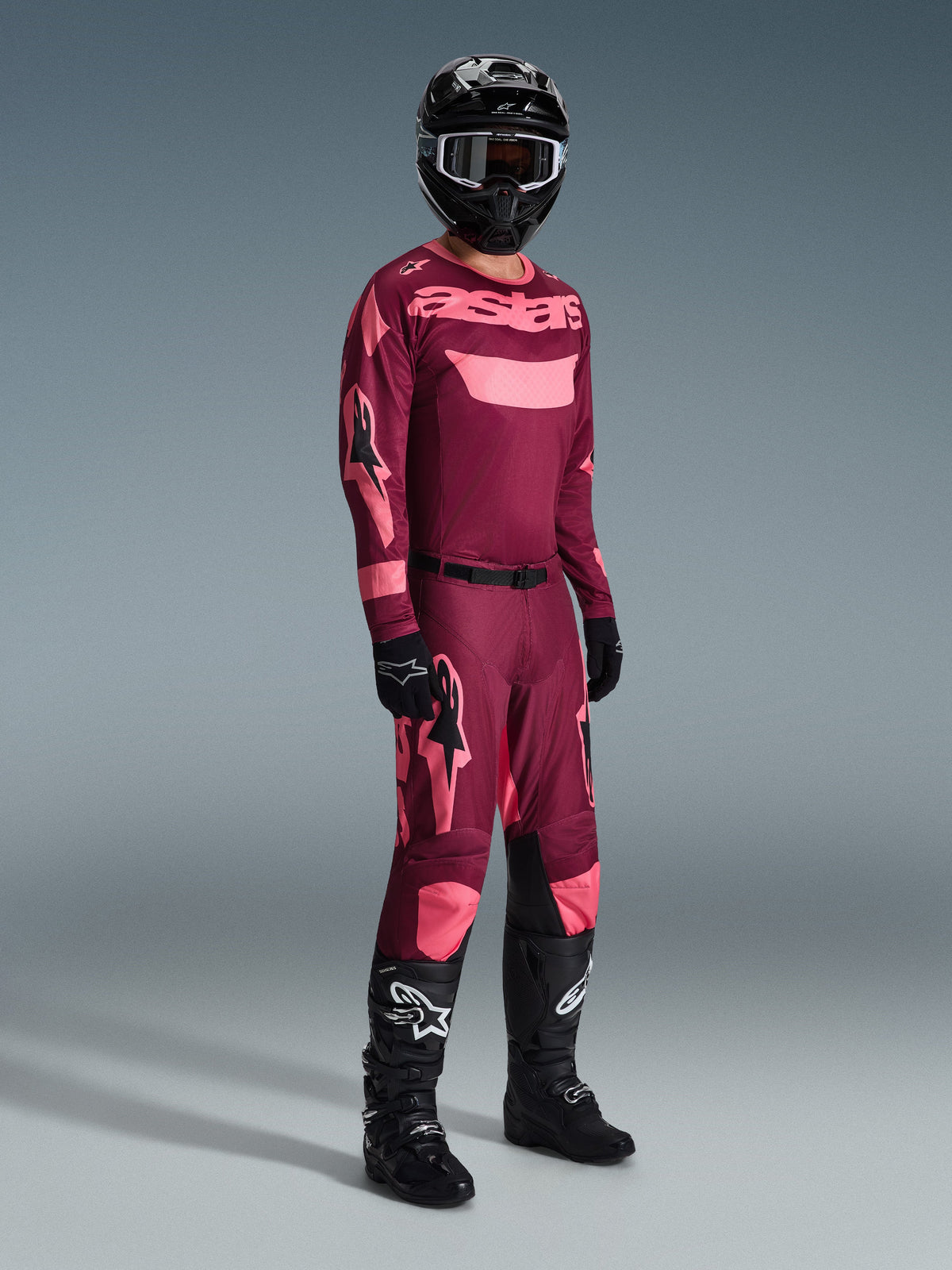 Alpinestars 2026 Racer Riway Pants, Motocross Pants, Dark Red Coral, worn with matching jersey, black helmet, and black boots, featuring pink Alpinestars logos and black knee panels, professional gear for off-road racing