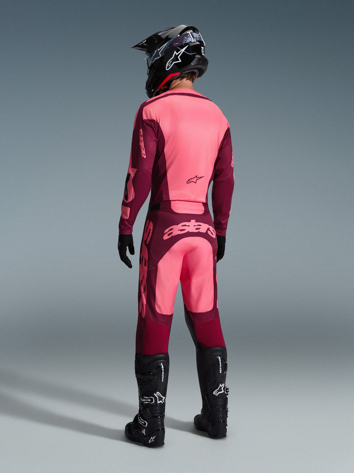 Alpinestars 2026 Racer Riway Pants, Motocross Pants, Dark Red Coral, rear view of a rider wearing a matching jersey, black helmet, and black boots, featuring bold coral branding on the seat and ergonomic athletic fit for off-road racing