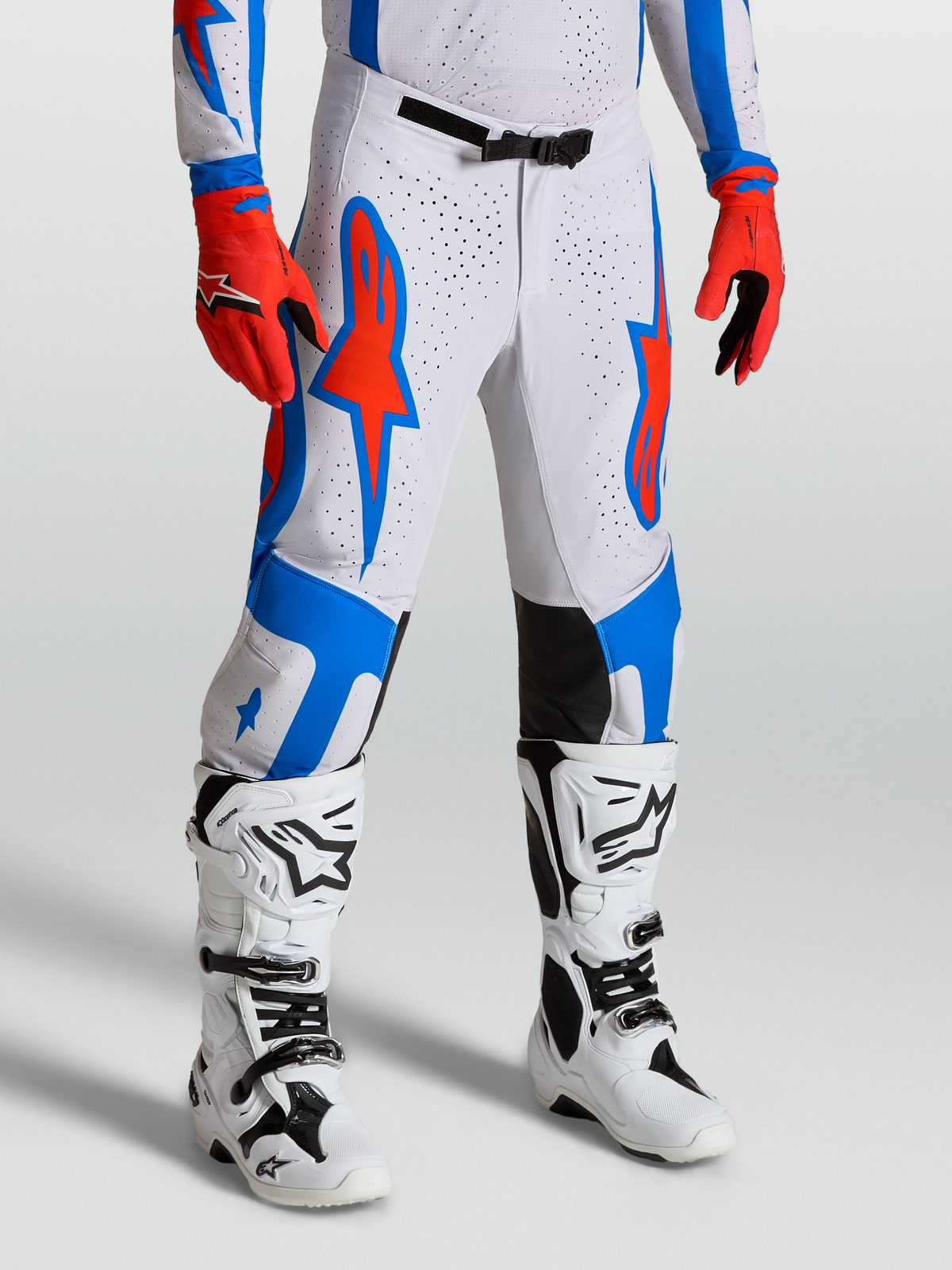 Alpinestars Supertech Vesta Hose, Motocross-Hose in Weiß und Rot mit blauen Stern-Grafiken, athletische Passform am Model, Offroad-Performance-Design.