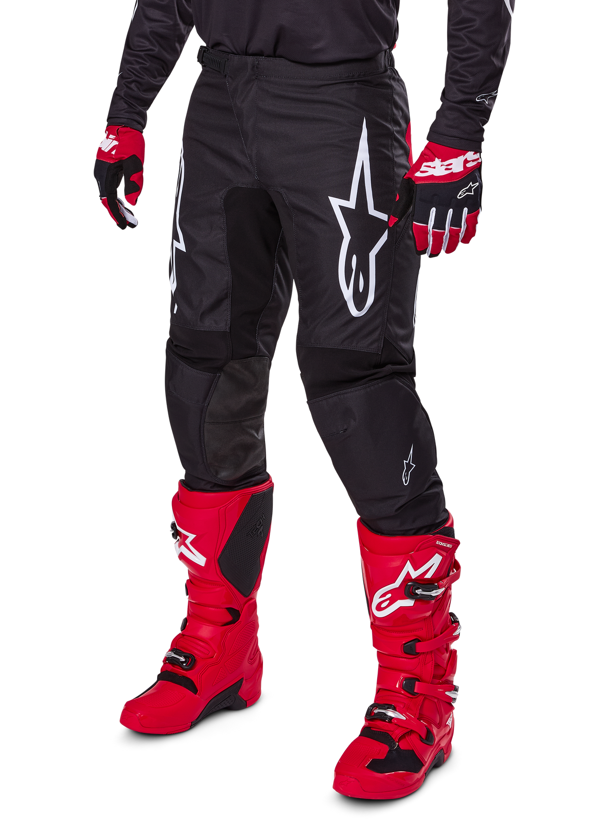 Alpinestars 2025 Fluid Haul Hose, Motocross-Hose, Schwarz, mit großem weißen Alpinestars-Logo, getragen mit leuchtend roten Stiefeln und rot-schwarzen Handschuhen, strapazierfähige 600D-Polygewebe-Konstruktion mit ergonomischem Schnitt für den Offroad-Rennsport