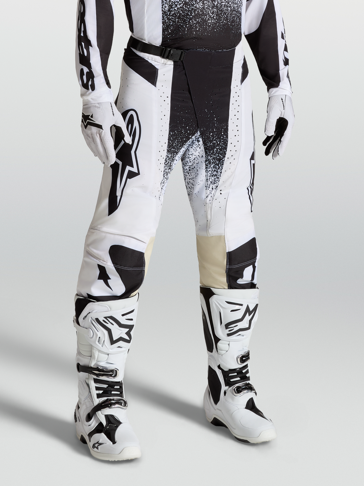 Alpinestars Techstar Swan Hose, Motocross-Rennausrüstung am Model, Weiß und Schwarz, aus strapazierfähigem Stretch-Ripstop mit passenden Stiefeln.