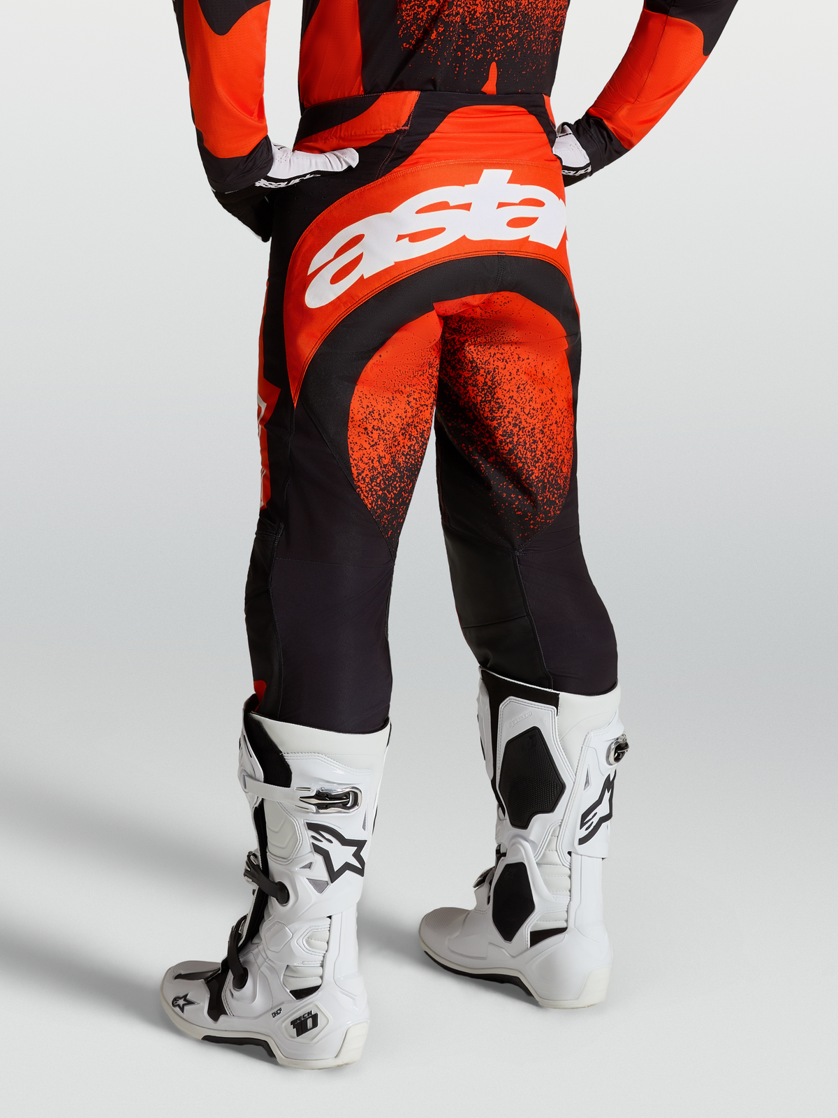 Alpinestars Techstar Swan Pants, Motocross Racing Pants for Men, Cardinal Red and Black, durable stretch chassis with white Astar branding on the rear, shown on-model with white Tech 10 boots.