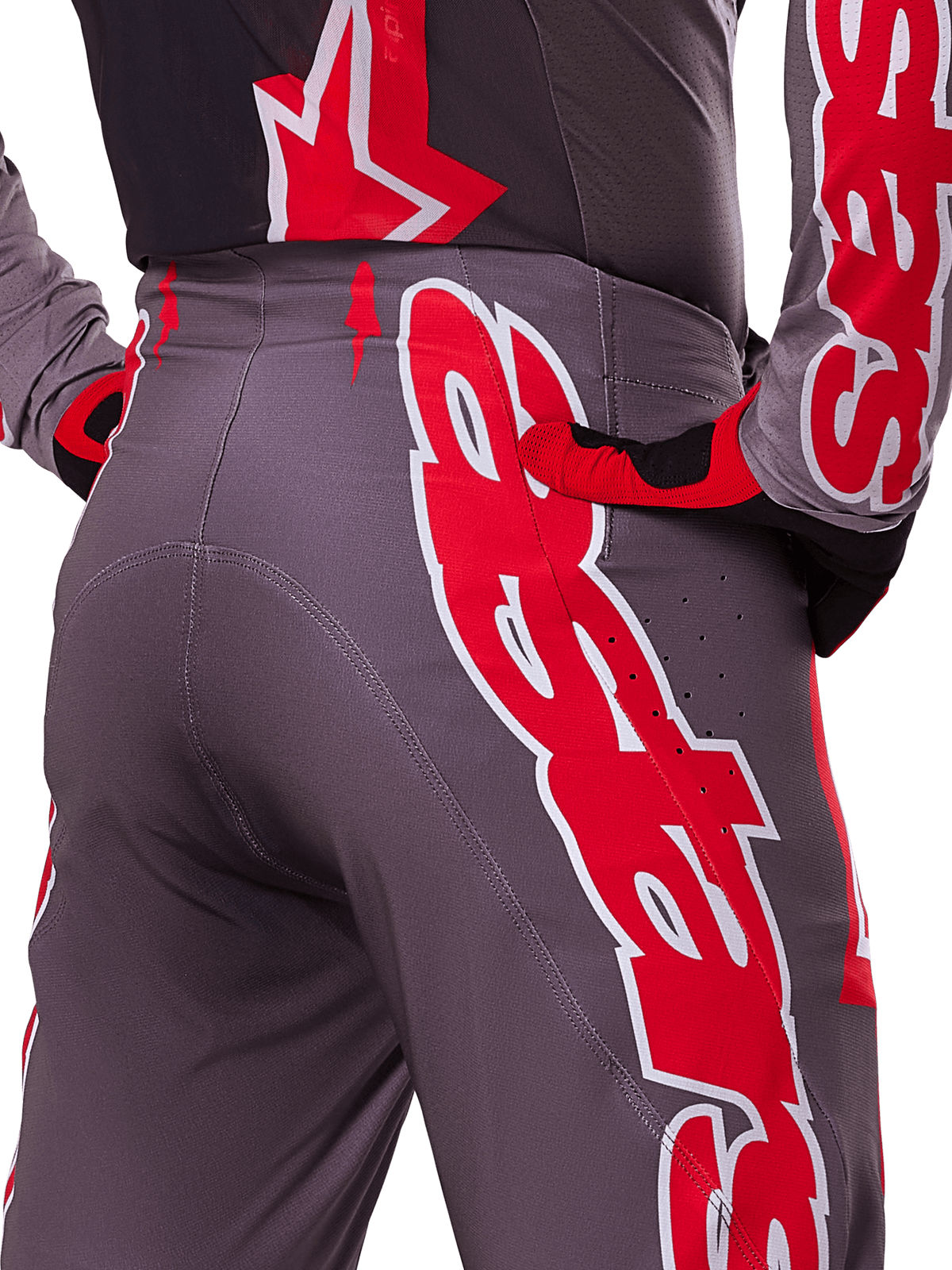 Alpinestars 2025 Supertech Lipan Hose, Motocross-Hose, Smoke Bright Red und Grau, Nahaufnahme von Hüfte und Gesäß mit markanten rot-weißen Logo-Grafiken, Belüftungsperforationen, athletische Rennpassform, getragen mit passender Ausrüstung.