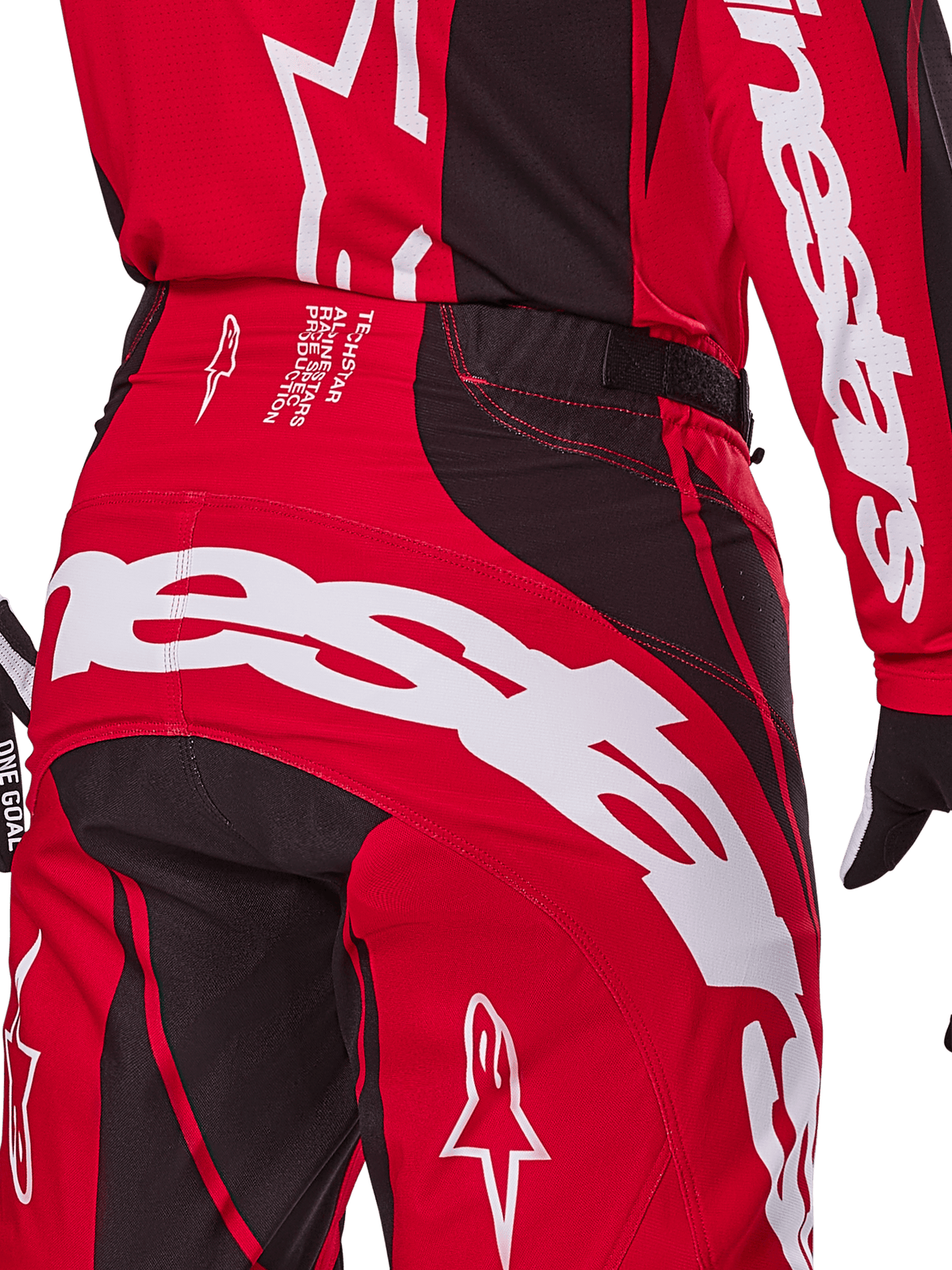 Alpinestars 2025 Techstar Dreem Hose, Motocross-Hose, Hellrot und Schwarz, Nahaufnahme des hinteren Taillen- und Gesäßbereichs mit auffälligem weißem Alpinestars-Branding, schwarzen Stretch-Einsätzen und technischem Produktionstext am Bund, entwickelt für Performance im Offroad-Rennsport.