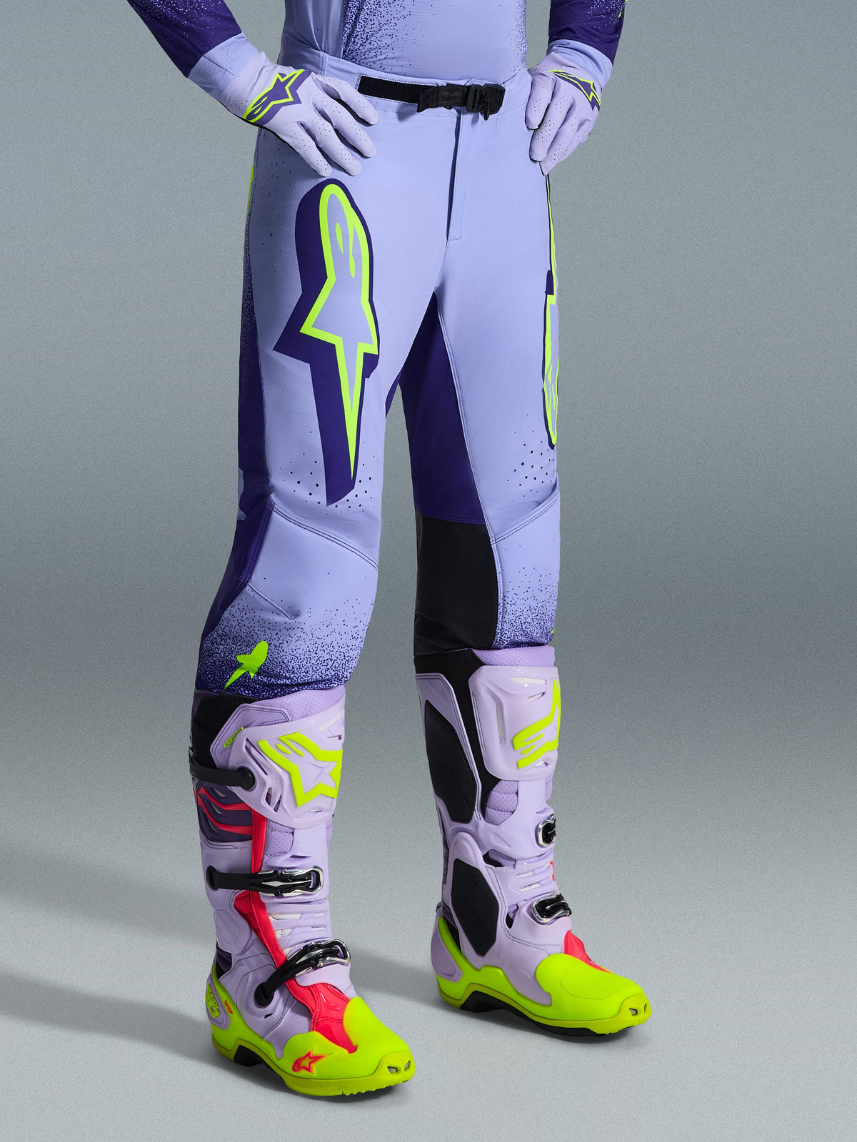 Alpinestars 2026 Supertech Scenz Hose, Motocross-Hose, Lila und Fluo-Gelb, getragen mit passenden Motocross-Stiefeln und Handschuhen, große neongelbe Logos, athletische Passform, lasergeschnittene Perforationen zur Belüftung