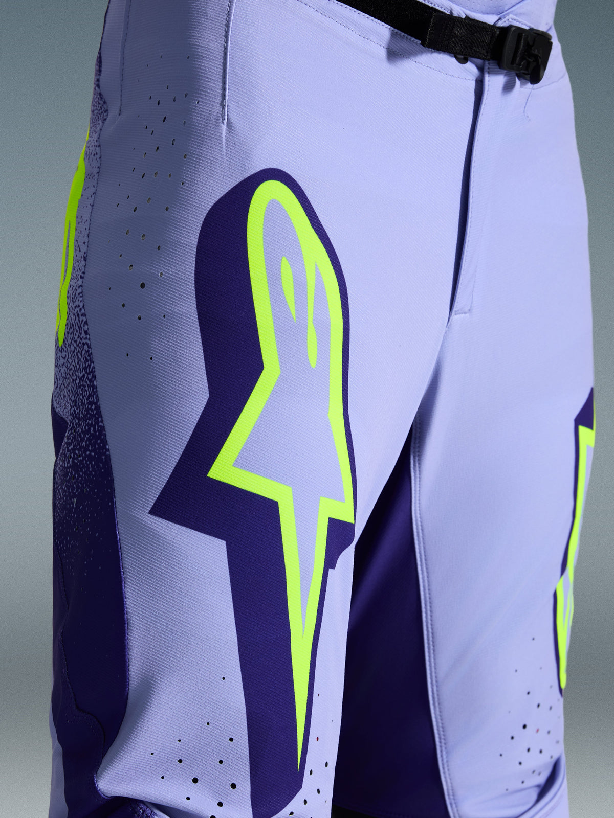 Alpinestars 2026 Supertech Scenz Hose, Motocross-Hose, Lila und Fluo-Gelb, Nahaufnahme mit großem gelben Logo auf dem Oberschenkel, lasergeschnittenen Perforationen zur Belüftung und magnetischem Bundverschluss, sportliche Offroad-Ausrüstung