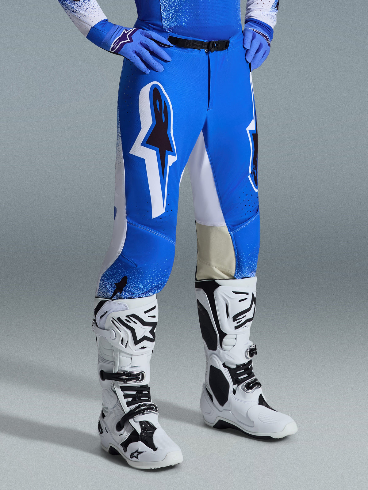 Alpinestars 2026 Supertech Scenz Hose, Motocross-Hose, Ucla-Blau und Weiß, getragen mit weiß-schwarzen Stiefeln und blauen Handschuhen, mit großen Grafik-Logos an den Oberschenkeln und weißen Einsätzen, athletische Passform für professionelles Motocross-Fahren