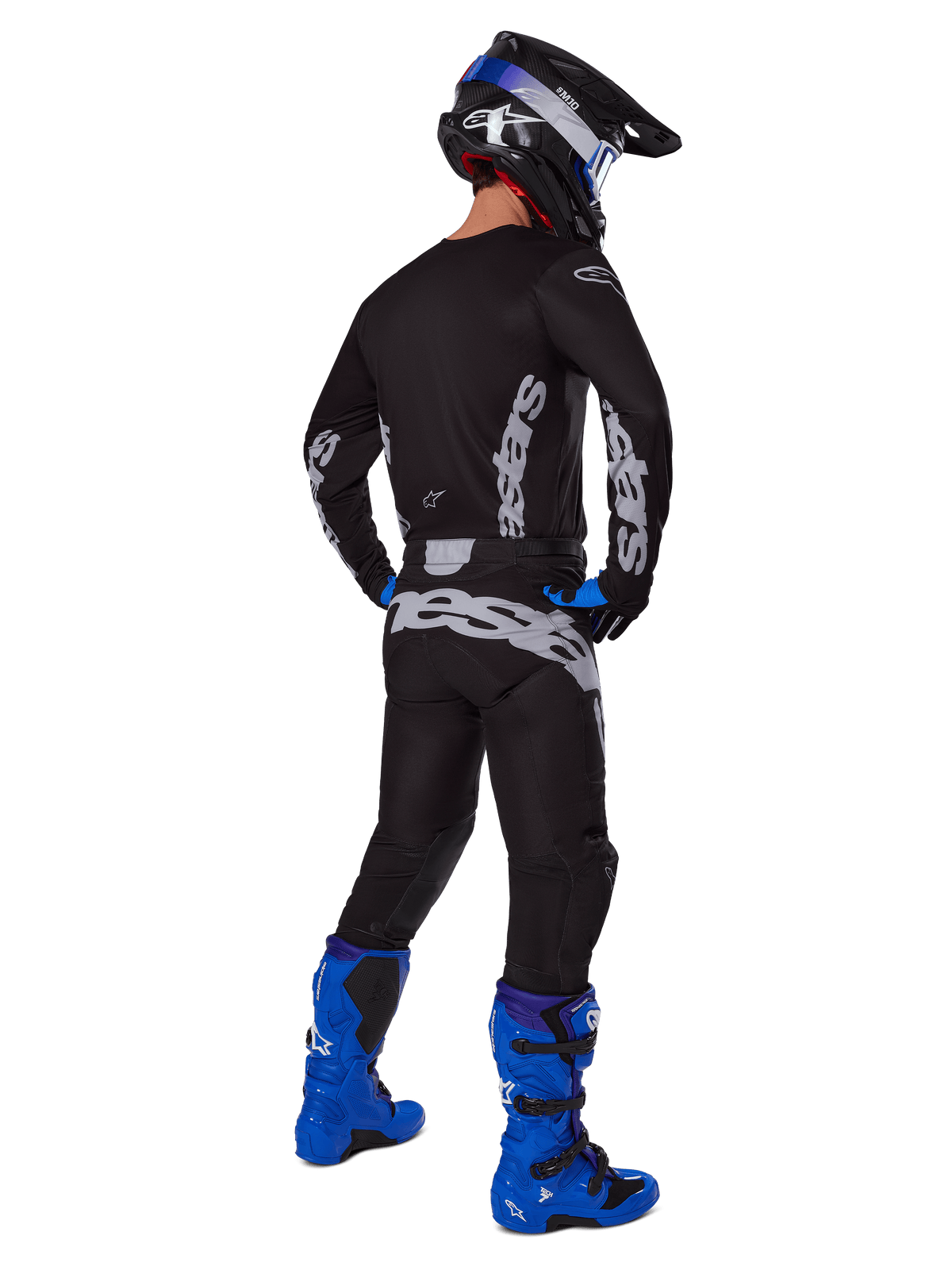 Alpinestars 2025 Racer Graphite Hose, Motocross-Hose, Schwarz und Grau, Rückansicht eines Fahrers in kompletter Ausrüstung mit passendem Trikot und leuchtend blauen Stiefeln, großes graues Branding am Gesäß, ergonomisch vorgeformtes Design für den Offroad-Rennsport
