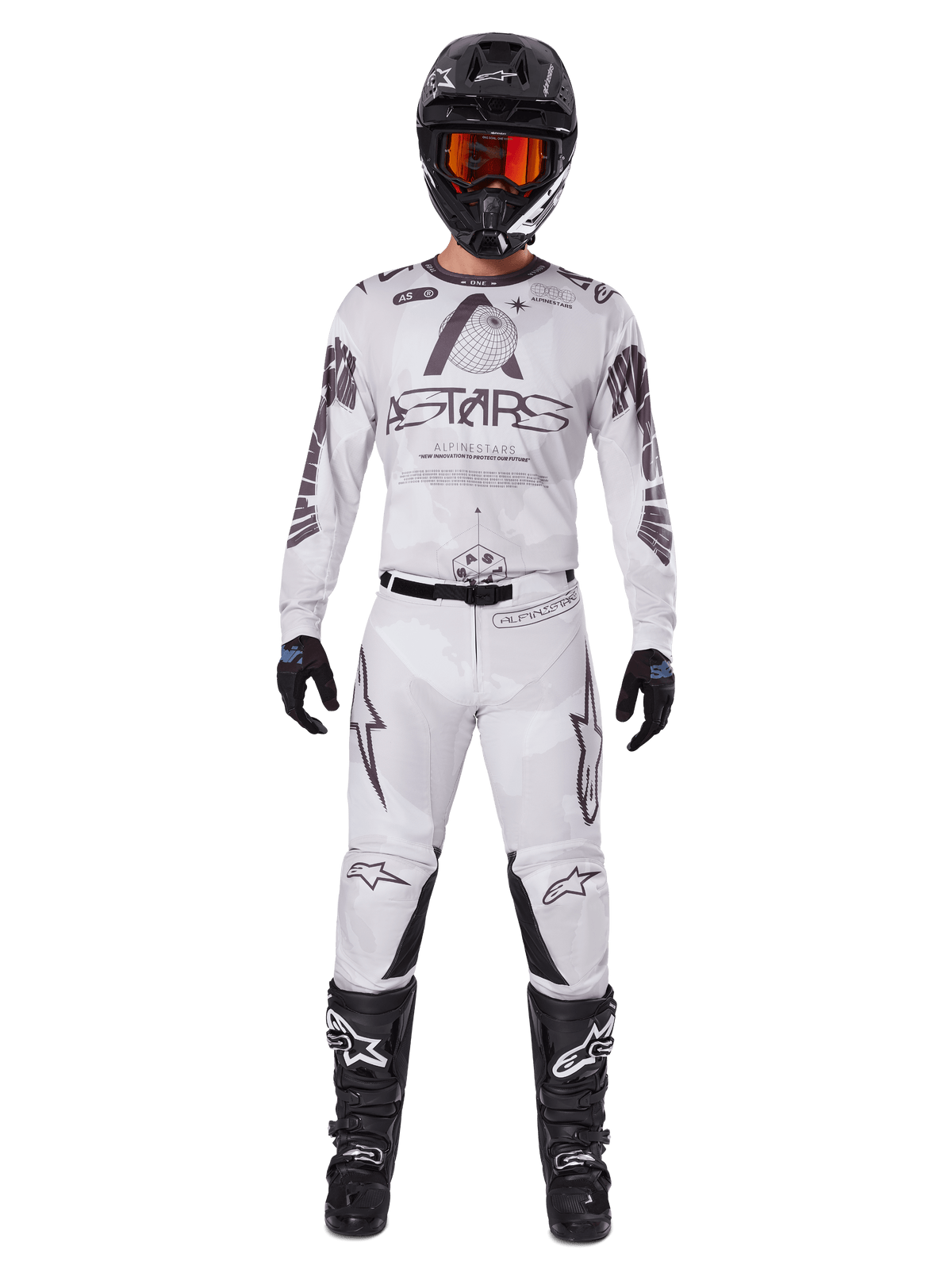 Motocross-Fahrer in der Alpinestars 2025 Racer Hollow Hose in Light Camo Brown, kombiniert mit einem passenden weiß-grauen Langarm-Trikot, schwarzem Helm mit orange-roter Brille, schwarzen Handschuhen und schwarzen Stiefeln, abgestimmtes Rennbekleidungs-Set für Offroad-Performance.