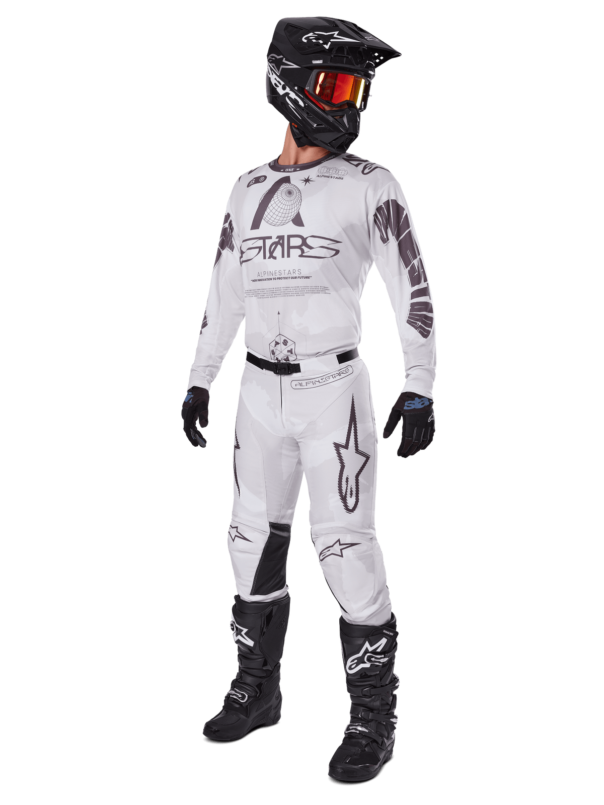 Alpinestars 2025 Racer Hollow Hose, Motocross-Hose, Light Camo Brown, gezeigt als Teil einer kompletten Rennausrüstung mit weißem Trikot, schwarzem Helm und schwarzen Stiefeln, mit verstärkten schwarzen Kniepaneelen und einem dezenten Camouflage-Design.