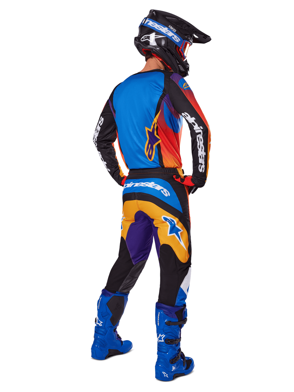 Motocross-Fahrer von hinten in der Alpinestars 2025 Fluid Wurx Hose, mehrfarbiges Design mit blauen, orangefarbenen, gelben und lila Akzenten, kombiniert mit einem passenden Trikot, leuchtend blauen Stiefeln und schwarzem Helm, komplette Offroad-Rennausrüstung.