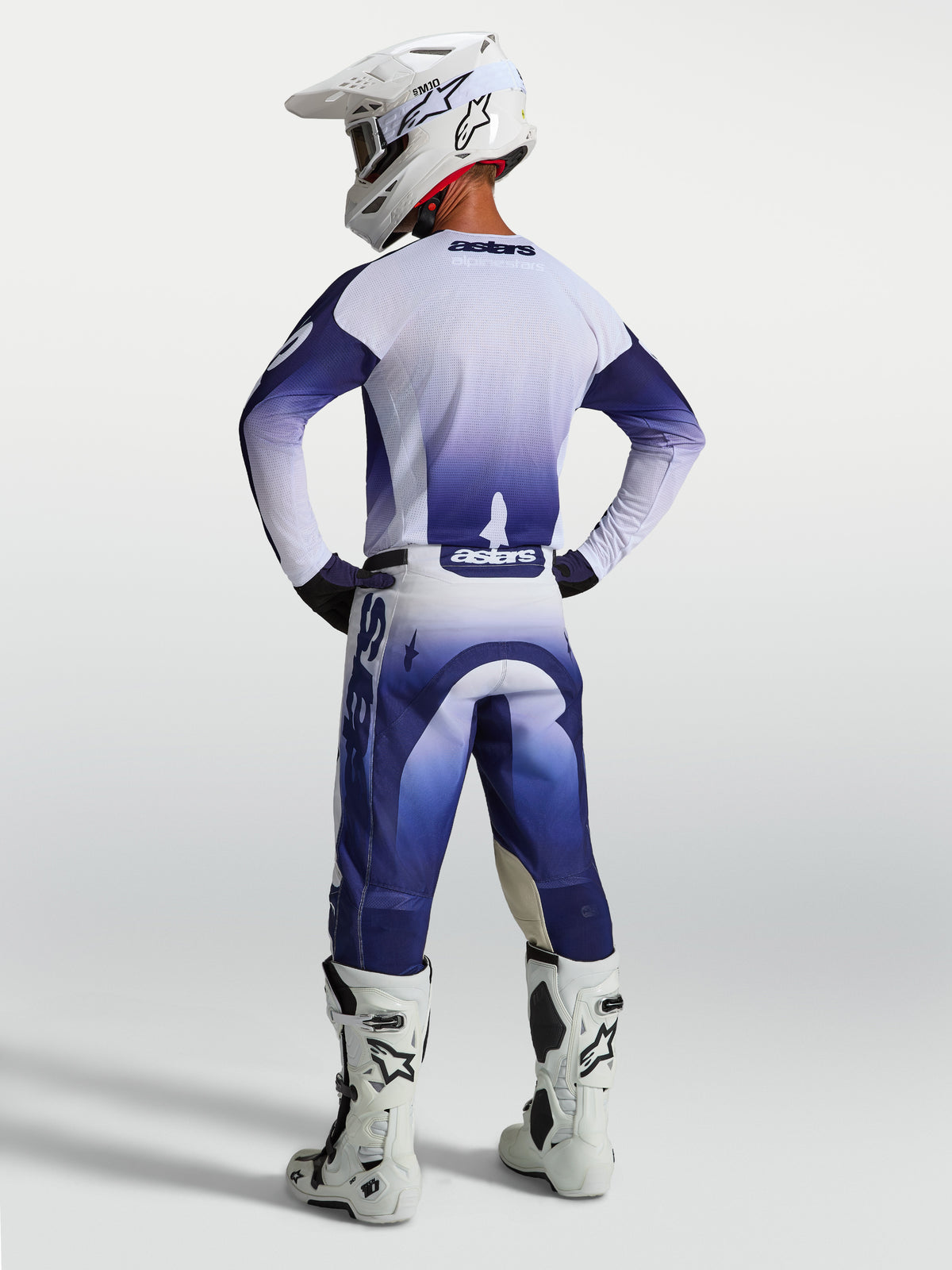 Alpinestars Racer Air Amber Hose, Herren-Motocross-Hose in Blau und Weiß, perforiert, Rückansicht am Fahrer mit Helm.