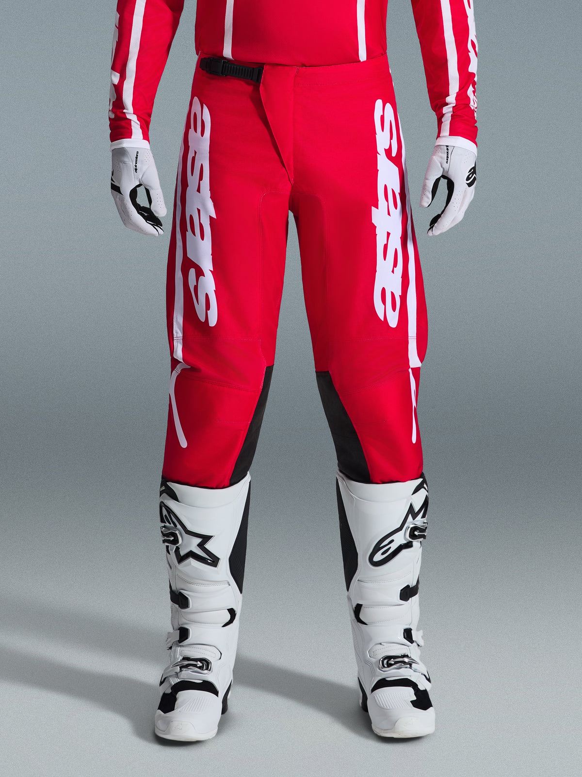 Alpinestars 2026 Fluid Apex Pants, Motocross Pants, Red and White, featuring large white Astars logos on the thighs and black inner knee panels, worn with matching white and black boots and gloves for a complete off-road racing look.