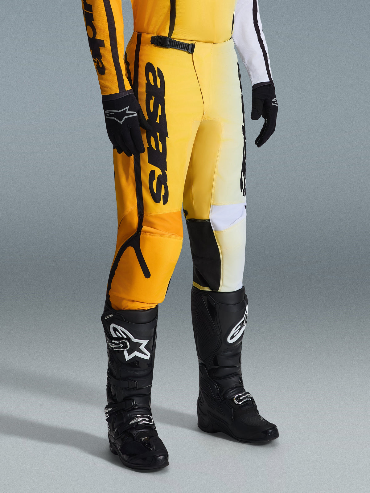 Alpinestars 2026 Fluid Apex Hose, Motocross-Hose, Gelb und Schwarz, getragen mit schwarzen Stiefeln und Handschuhen, markantes 'astars'-Branding auf dem Oberschenkel, ergonomisches Design mit verstärkten Einsätzen, strapazierfähiges Material für den Offroad-Einsatz