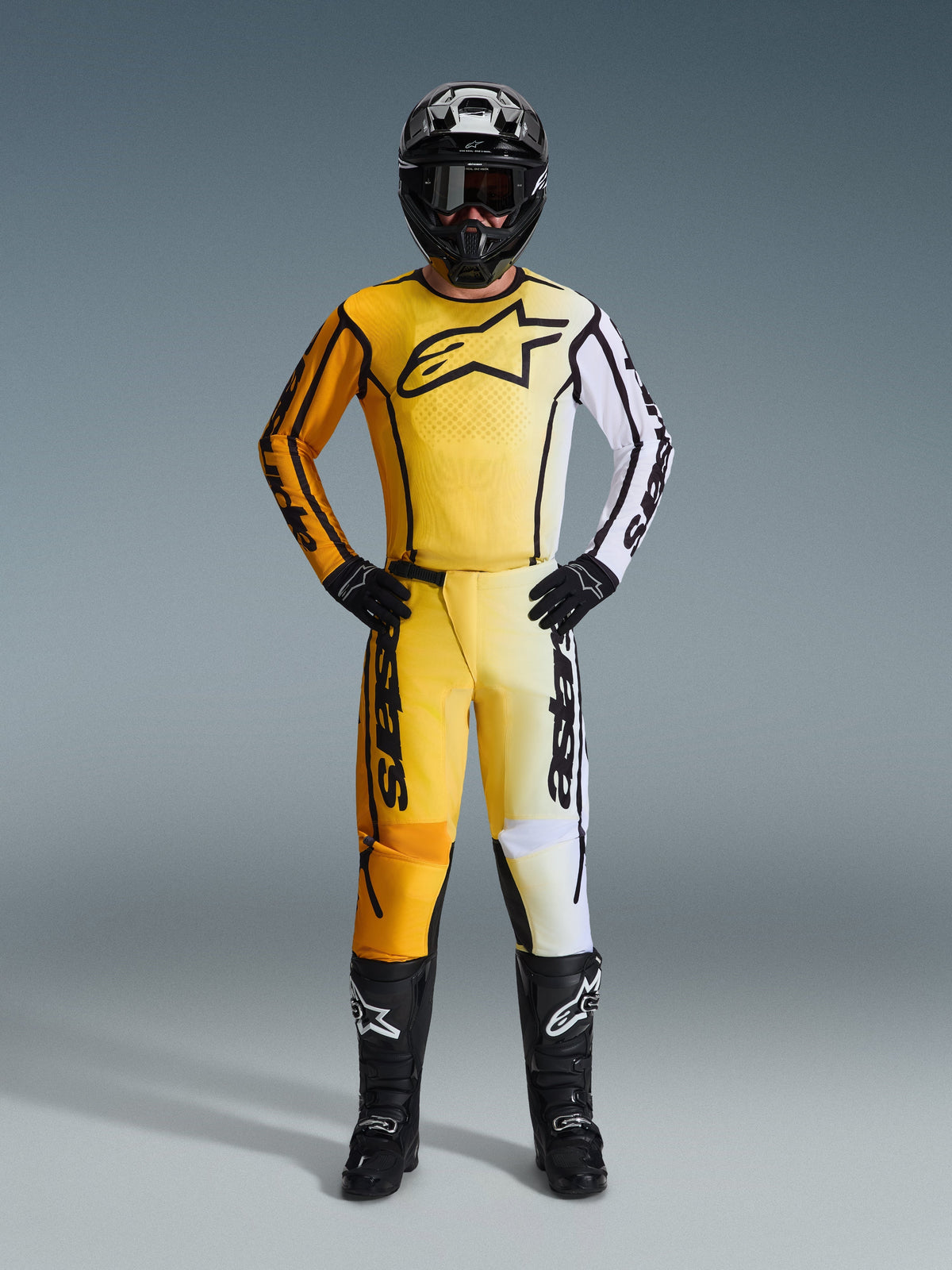 Alpinestars 2026 Fluid Apex Hose, Motocross-Hose in Gelb, Schwarz und Weiß, getragen als komplettes Rennset mit passendem Jersey mit Farbverlauf, schwarzem Helm und Stiefeln, professionelle Offroad-Ausrüstung.