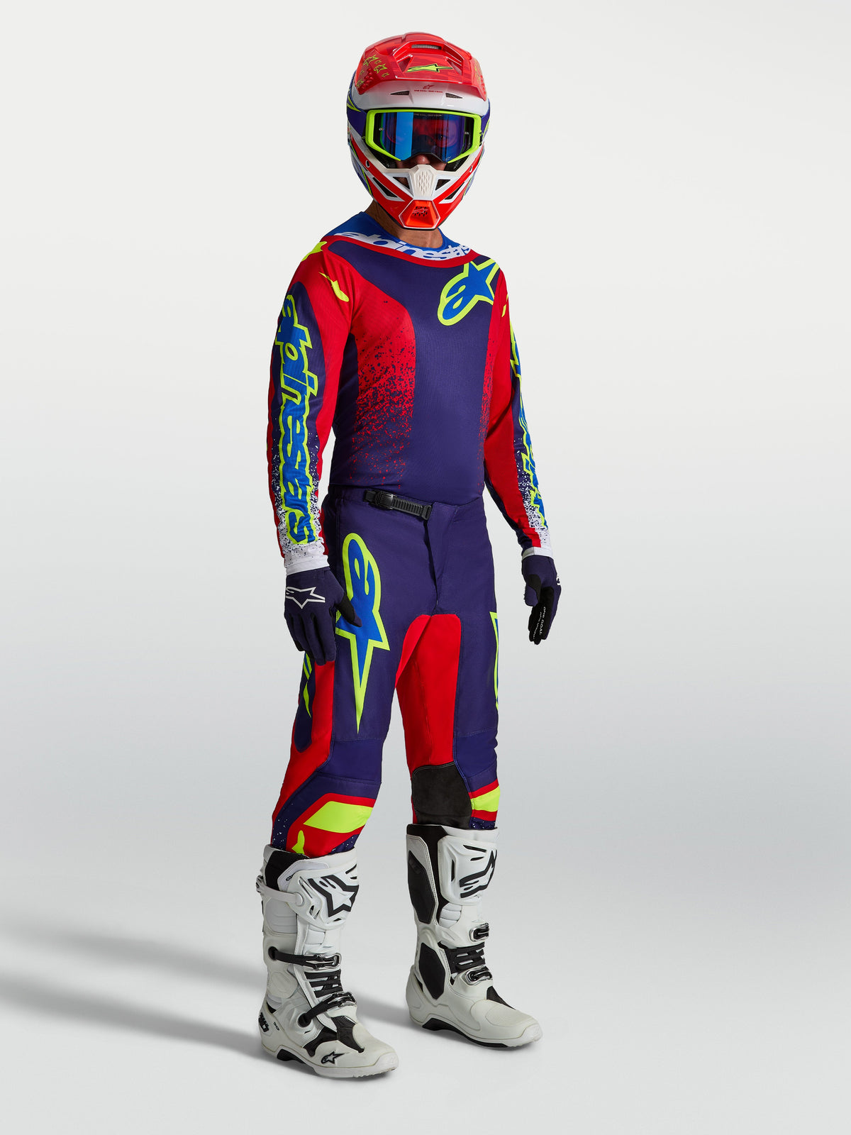 Alpinestars Fluid Drag Gear Set und Hose, Herren-Motocross-Outfit in Marineblau und Rot mit weißen Rennstiefeln am Model.