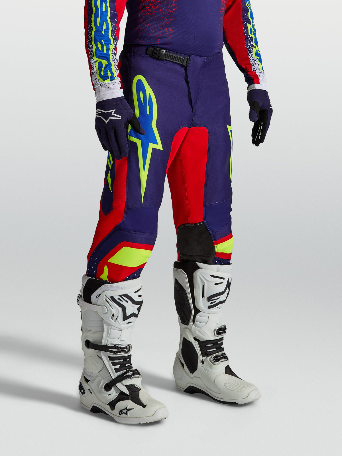 Alpinestars Fluid Drag Hose, Motocross-Hose für Herren, Blau und Rot mit auffälligen Grafiken und weißen Motorradstiefeln.