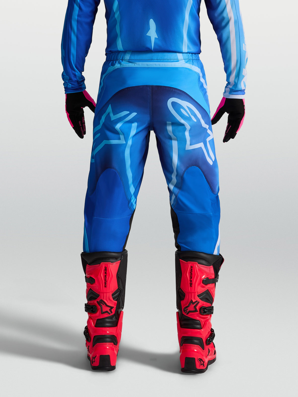 Alpinestars Fluid Kepler Hose, Herren Motocross-Hose in Blau, 600D-Polygewebe, Rückansicht am Model mit roten MX-Stiefeln.