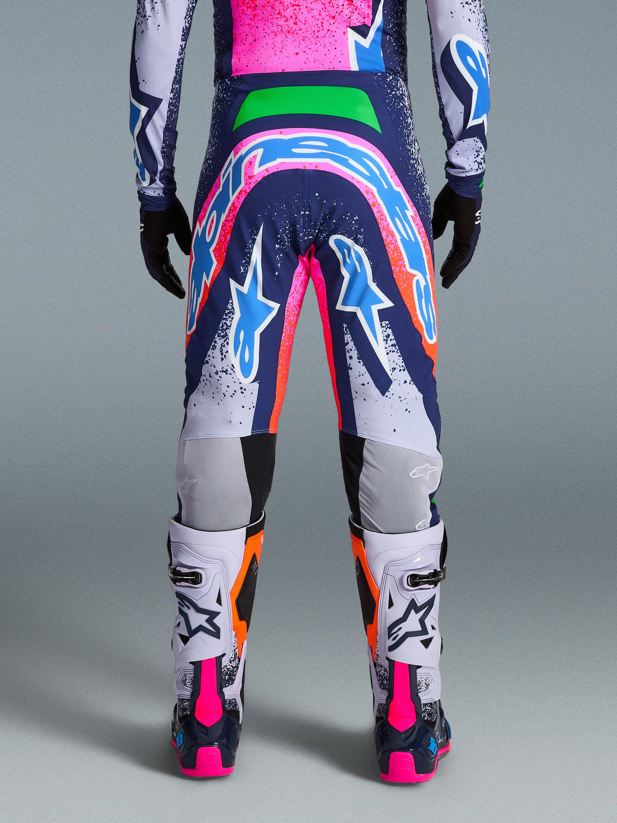 Alpinestars Limited Edition Supertech Records Pants, Motocross Pants, Multicolor with vibrant pink, blue, orange, and white graphics, rear view showing large logo on the seat, worn with matching jersey and white boots, pro-level athletic fit for off-road racing.