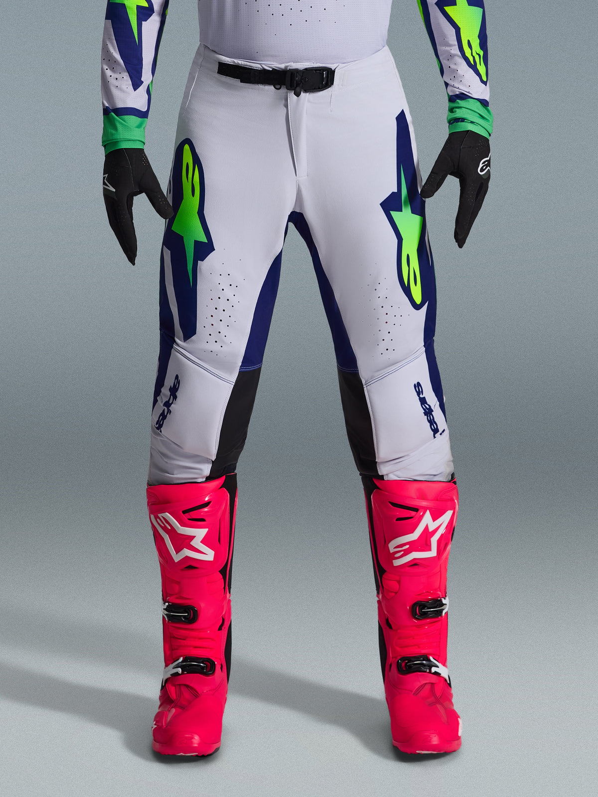 Alpinestars 2026 Supertech Vista Gear Set, Motocross pants in white with blue and lime green accents, paired with vibrant pink boots and black gloves, professional-grade racing gear with athletic fit and laser-cut perforations.