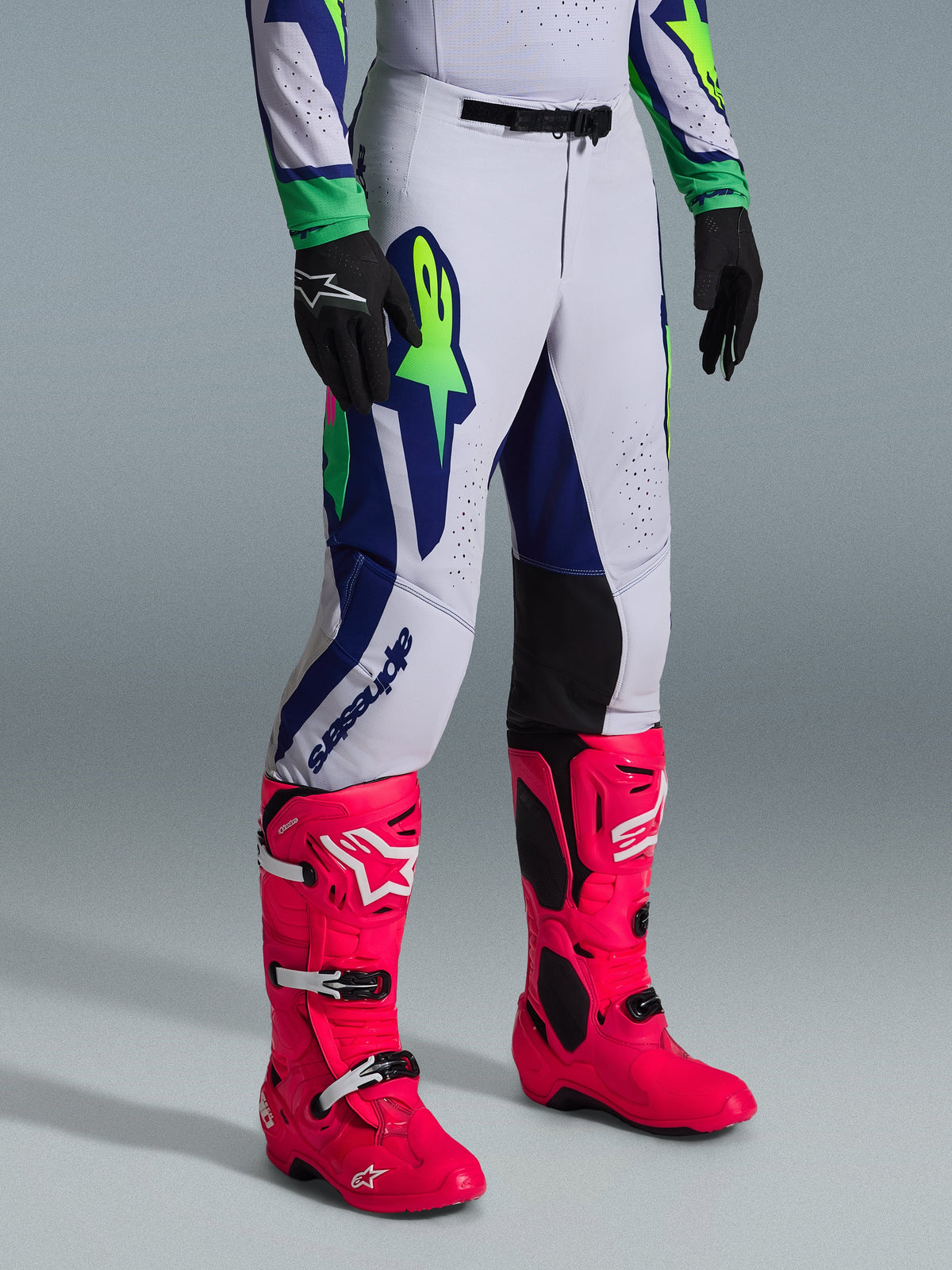Alpinestars 2026 Supertech Vista Gear Set, Motocross Pants, Light Gray with Navy Blue and Lime Green accents, worn with bright pink boots and black gloves, featuring a professional athletic fit and bold graphics