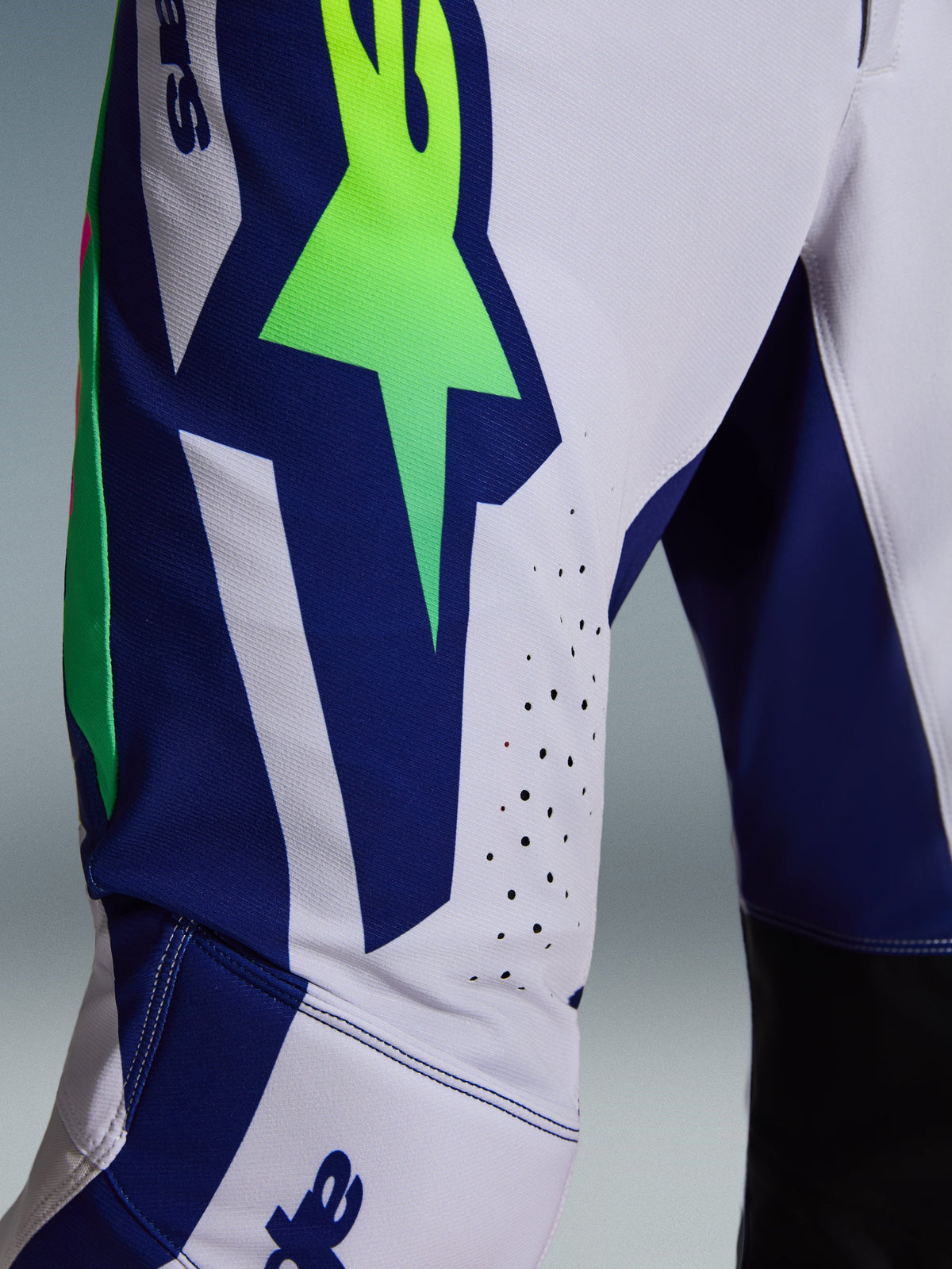 Alpinestars 2026 Supertech Vista Pants, Motocross Pants, Light Gray with Yellow Fluo and Blue accents, close-up view of the thigh showing the large A-star logo, laser-cut ventilation holes, and advanced stretch rip-stop fabric.