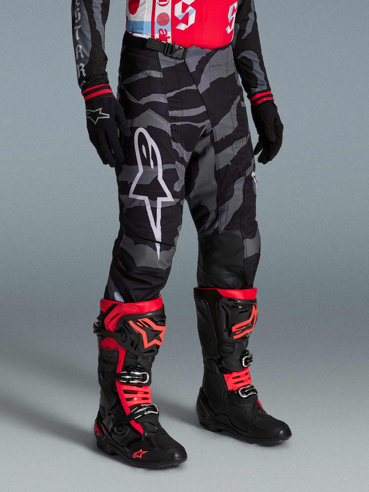 Alpinestars Techstar Beast Coast Hose, Camouflage-Motocross-Hose mit weißem Logo und rot-schwarzen Stiefeln.