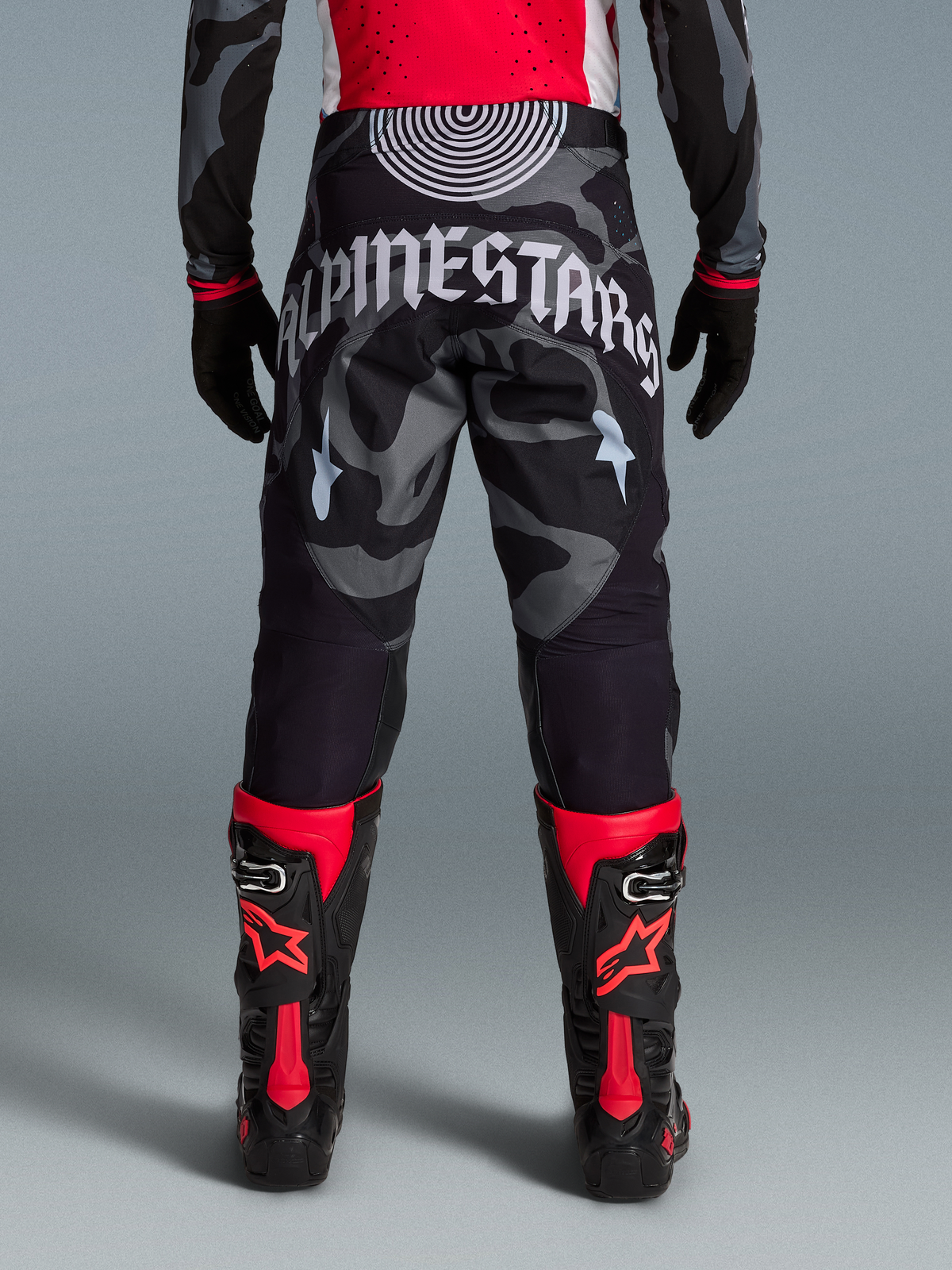 Alpinestars Techstar Beast Coast Hose in Camouflage mit weißem Schriftzug am Gesäß und rot-schwarzen Stiefeln.