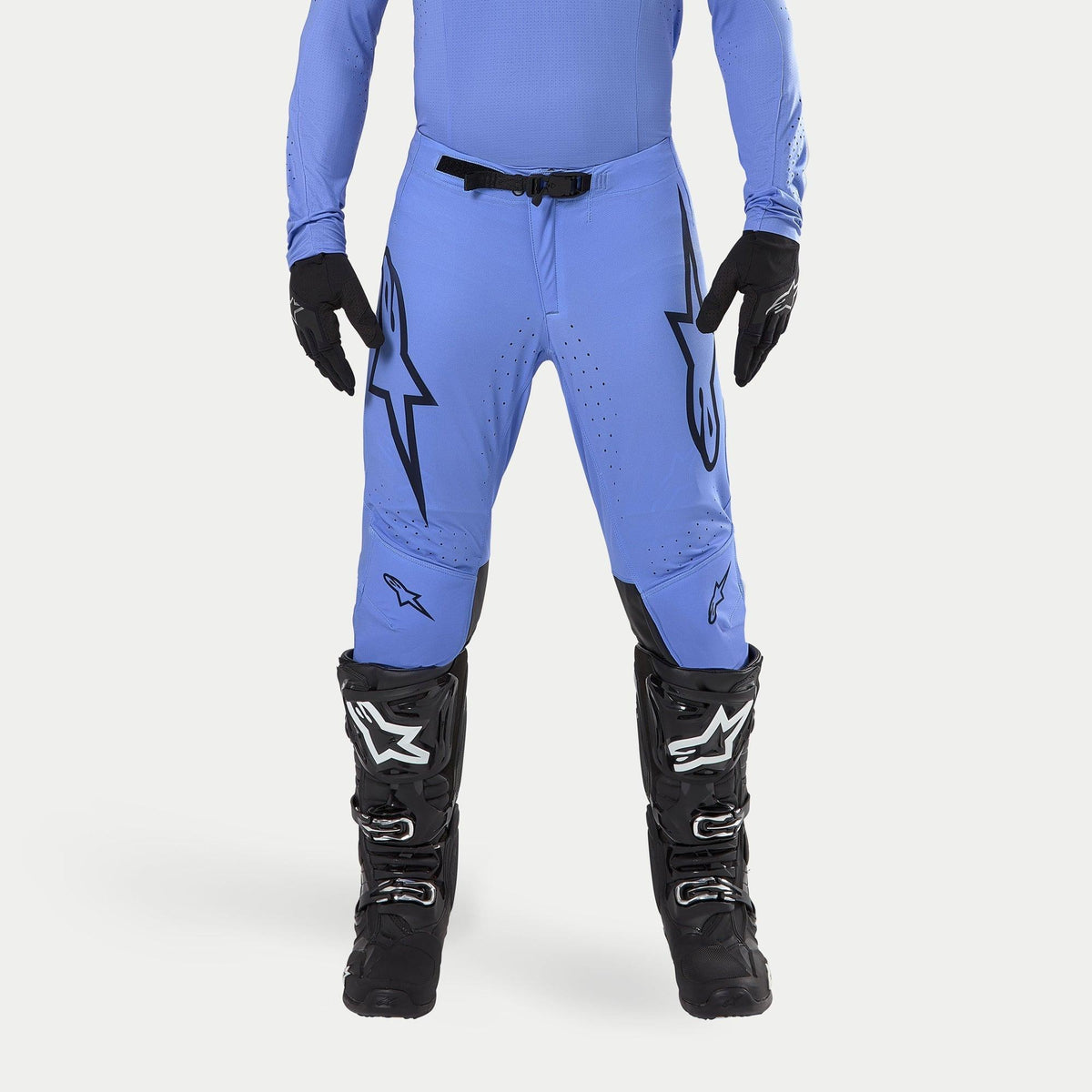 Alpinestars 2024 Supertech Dade Pants, Motocross Pants, Light Blue, featuring large black Astars logos on the thighs, black waist buckle, worn with black motocross boots and matching blue top, professional off-road racing apparel