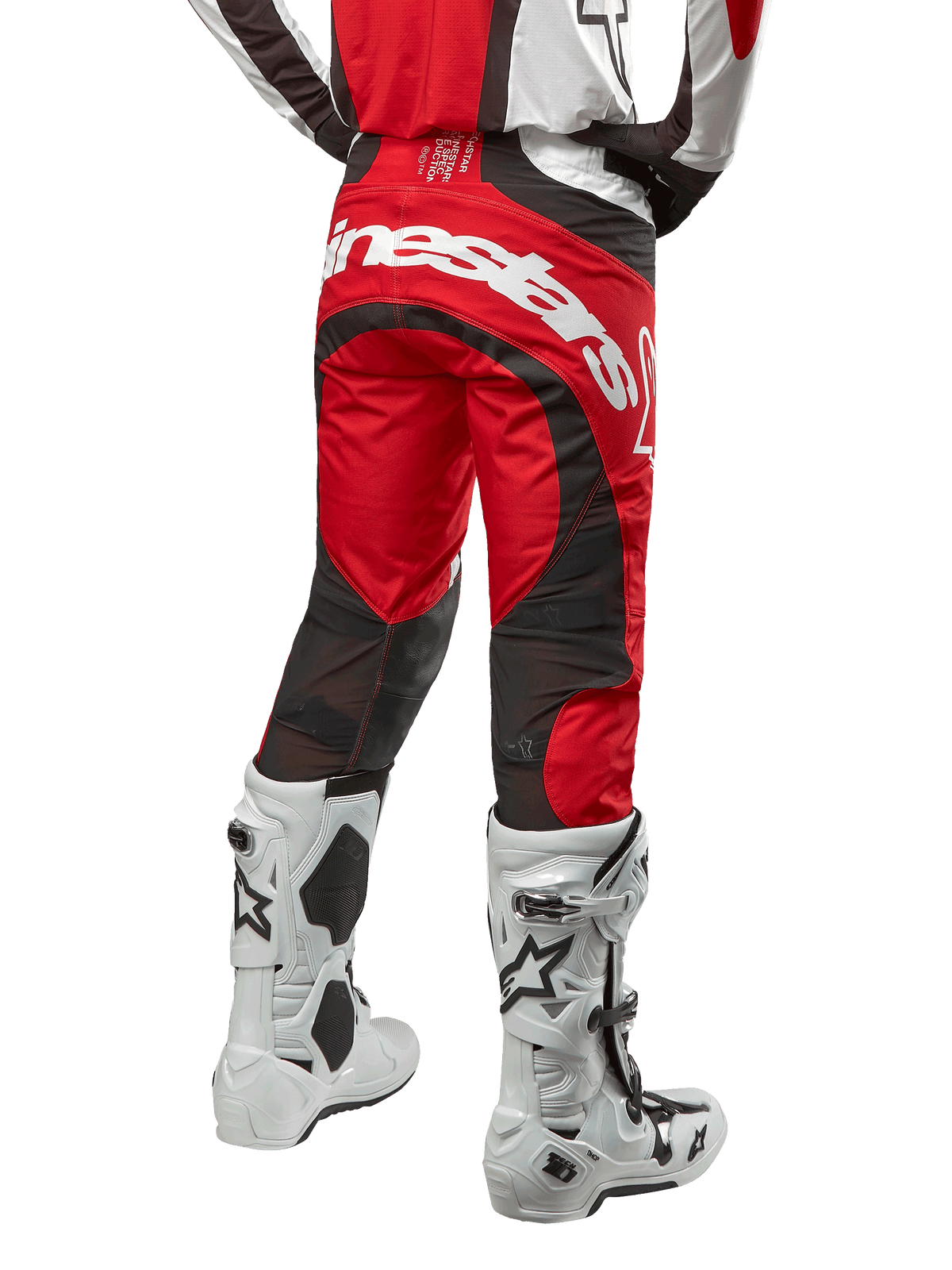 Alpinestars 2024 Techstar Ocuri Hose, Motocross-Hose, Mars Red, Weiß und Schwarz, Rückansicht mit großem weißem Alpinestars-Logo auf dem Gesäß, schwarze Mesh-Belüftungseinsätze, getragen mit weiß-schwarzen Motocross-Stiefeln, athletisches Race-Fit-Design für das Offroad-Fahren