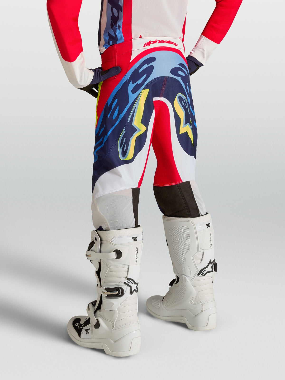 Alpinestars Youth Supertech Dyna Pants, fire red and navy blue motocross trousers for young riders, shown from the rear.