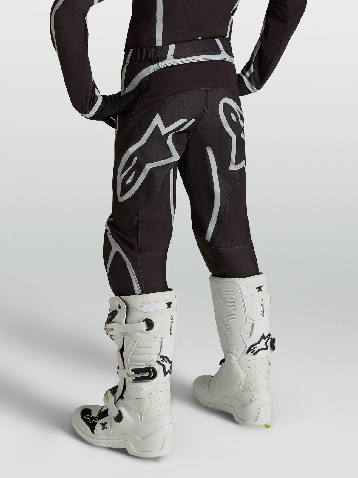 Alpinestars Jugend Fluid Apex V2 Hose, Motocross-Hose, Schwarz und Silber, Rückansicht mit weißen Motocross-Stiefeln.