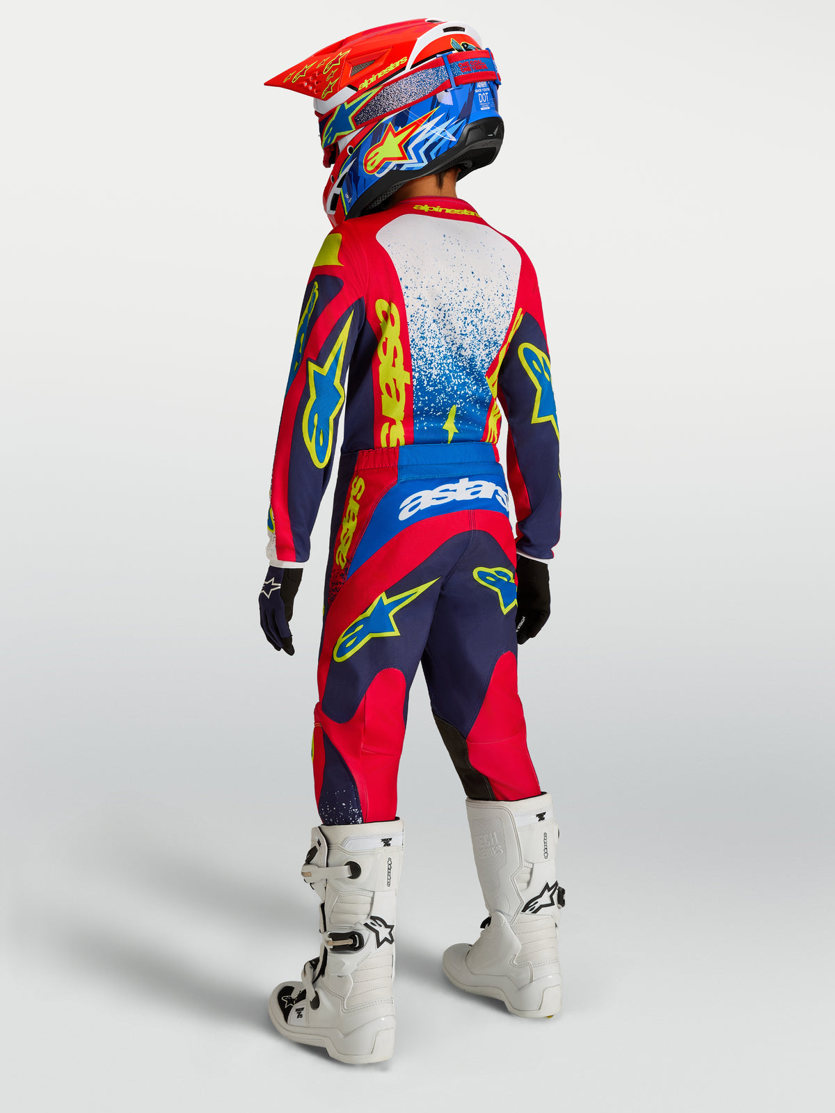 Alpinestars Youth Fluid Drag Pants, navy blue and fire red motocross trousers with reinforced seat and white racing boots.
