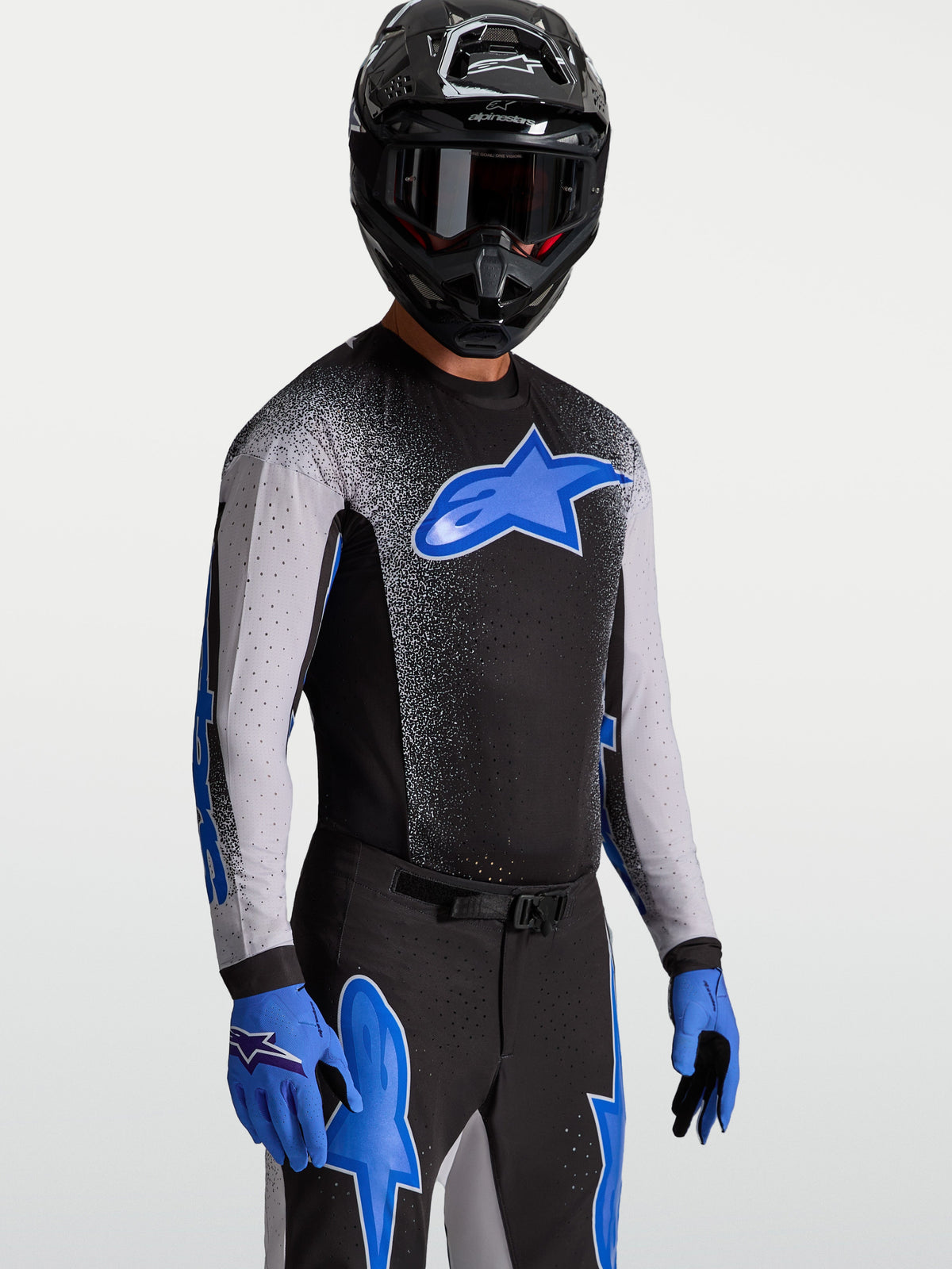 Alpinestars Supertech Hiten AFD Trikot, Motocross-Renntrikot für Herren, Schwarz und Blau, mit Stretch-Mesh, am Model mit Helm und Handschuhen gezeigt, athletische Passform.