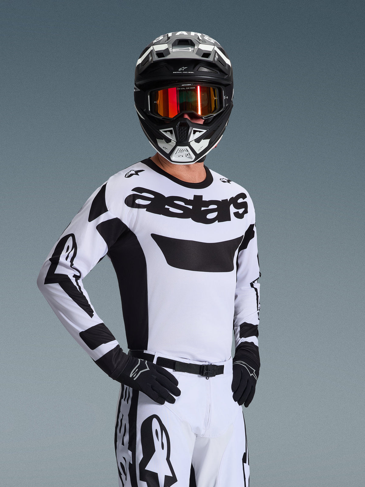 Alpinestars 2026 Racer Riway Trikot, Motocross-Trikot, Weiß und Schwarz, mit markantem „astars“-Logo auf der Brust, getragen mit passender weißer Hose und schwarzen Handschuhen, schwarz-weißer Helm mit rot verspiegelter Brille, professionelle Offroad-Rennausrüstung