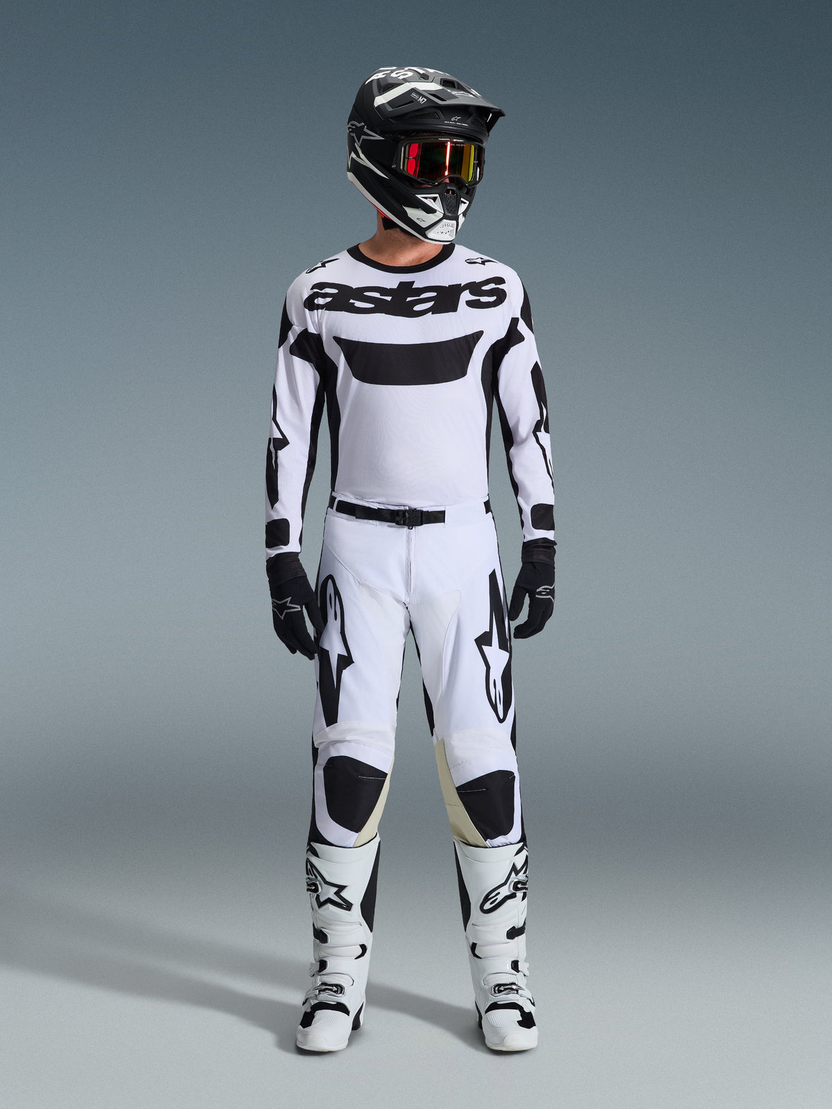 Alpinestars 2026 Racer Riway Trikot, Motocross-Trikot, Weiß und Schwarz, getragen als komplettes Racing-Kit mit passender Hose, schwarzer Helm mit roter Brille, schwarze Handschuhe und weiße Stiefel, mit markantem schwarzen „astars“-Branding und Stern-Logos.