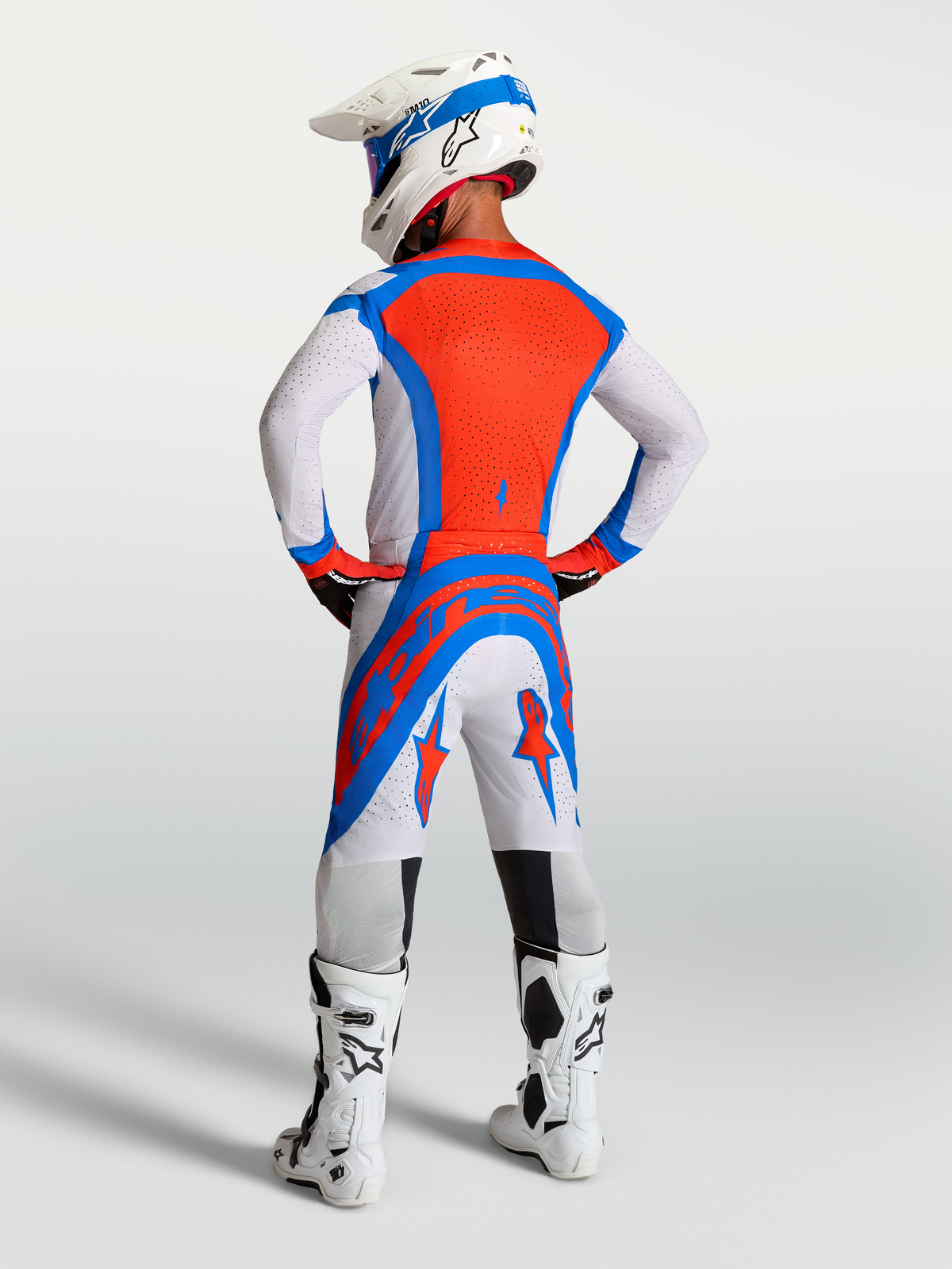 Alpinestars Supertech Vesta Motocross-Ausrüstungsset, Helllila und Kardinalrot, Rückansicht am Fahrer mit Helm und Stiefeln.