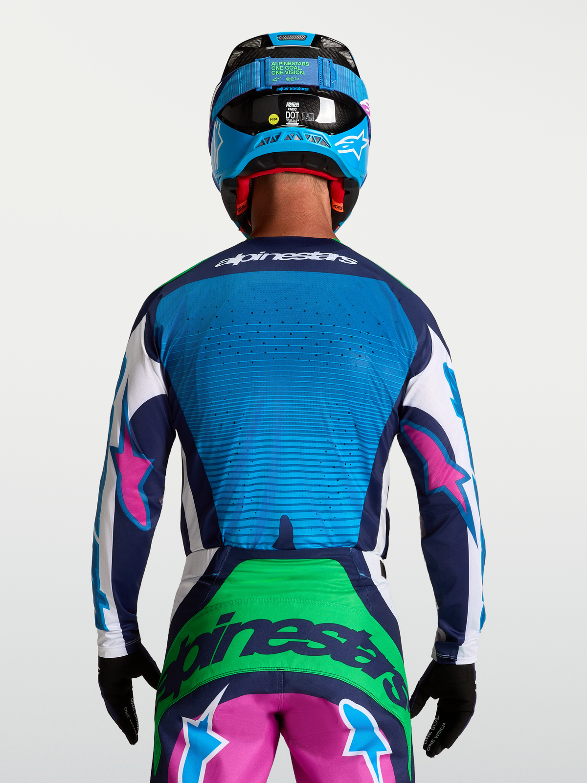 Alpinestars Techstar Maven Trikot, Motocross-Renntrikot in Blau und Grün mit pinken Details, Rückansicht am Model mit Helm, lasergeschnittene Belüftung