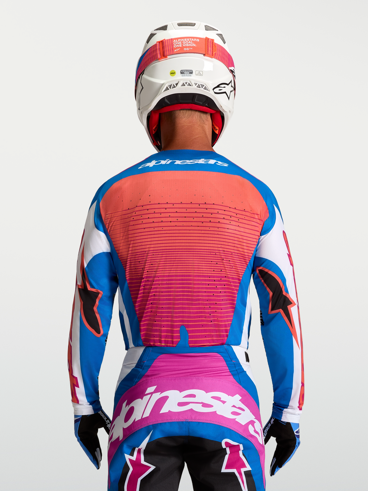 Alpinestars Techstar Maven Trikot, Rückansicht am Fahrer, Blau und Korallenrot, athletische Motocross-Passform mit Belüftung.