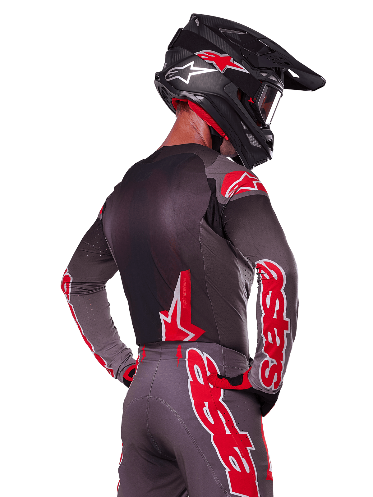 Alpinestars 2025 Supertech Lipan Ausrüstungsset, Rückansicht eines Motocross-Fahrers, anthrazitgraues Trikot und Hose mit leuchtend rotem 'astars'-Branding auf den Ärmeln und dem Rücken, kombiniert mit einem schwarzen Helm